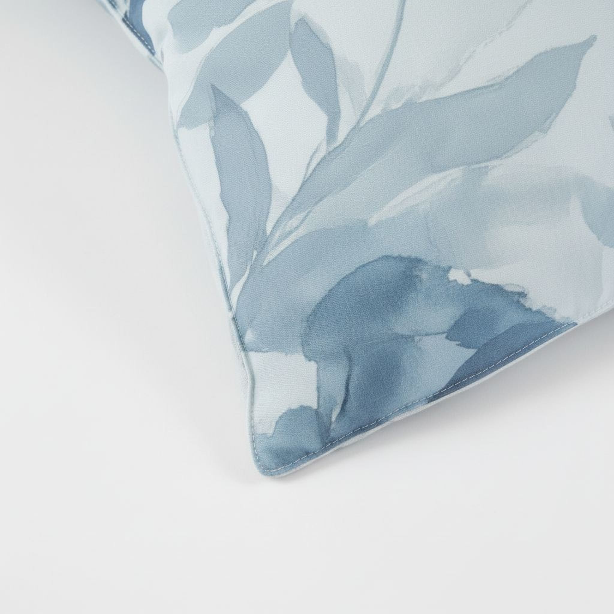 A close-up view of a blue and white patterned pillow or cushion, with a watercolor-like texture.