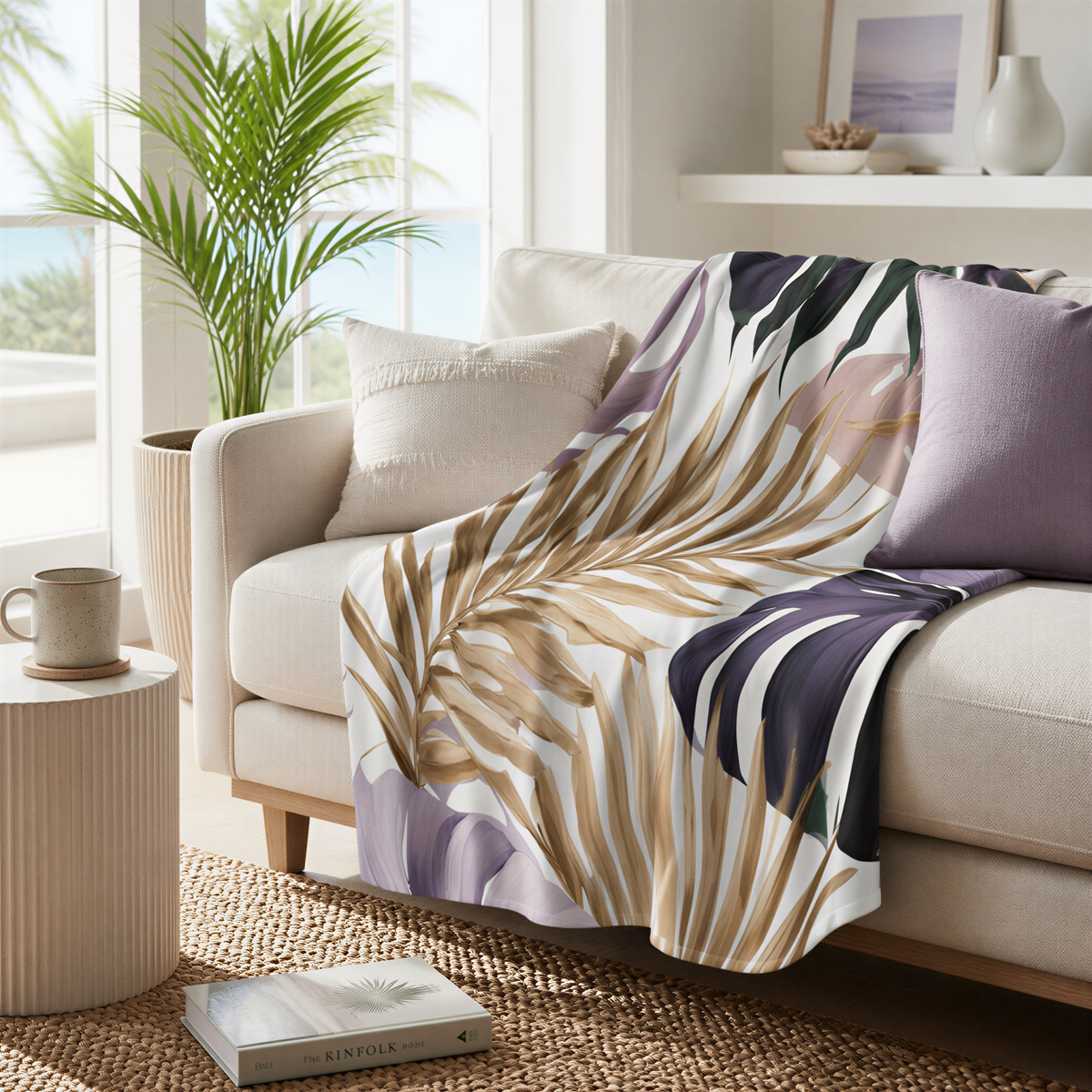a cozy living room with a white sofa adorned with a colorful throw blanket featuring a tropical leaf pattern. The room is decorated with a potted plant, a coffee table, and a bookshelf, creating a warm and inviting atmosphere.
