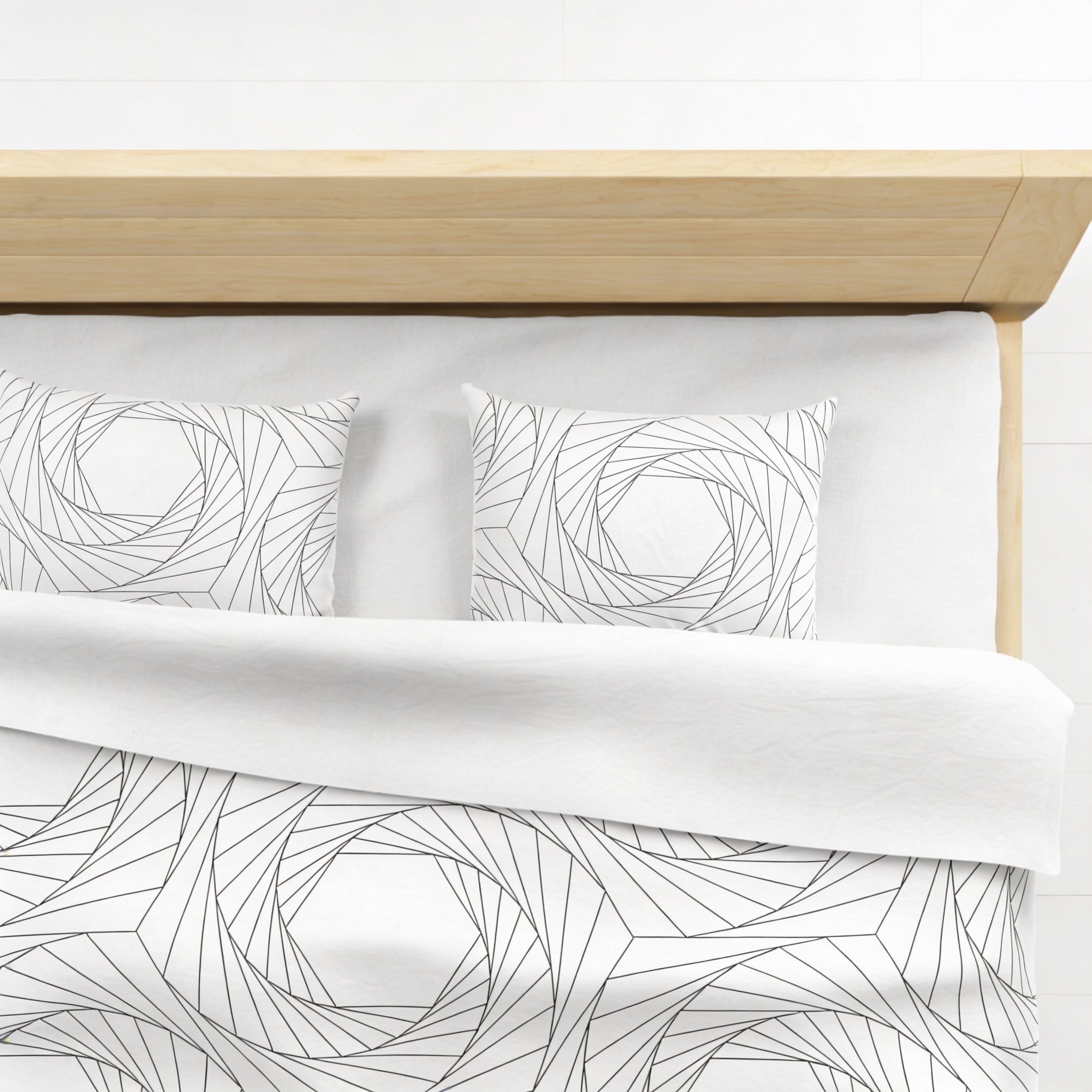 a neatly made bed with a white comforter and pillows featuring a geometric pattern in black and white.