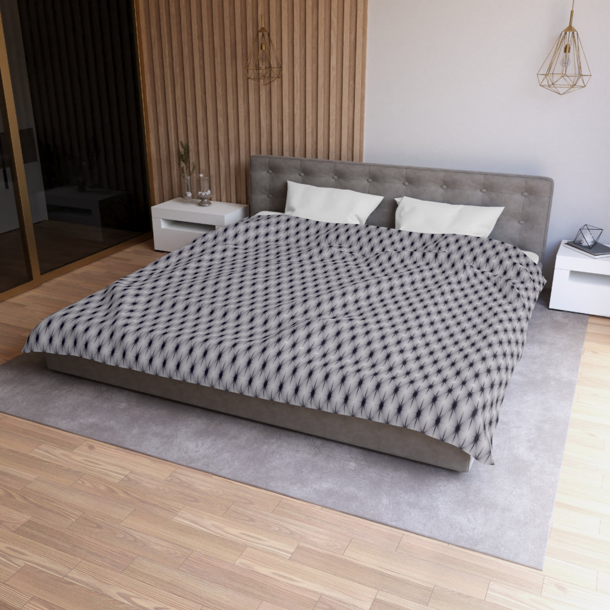 a modern bedroom with a large bed, a gray headboard, and a patterned comforter. The room has a wooden floor and white walls, creating a clean and minimalist aesthetic.