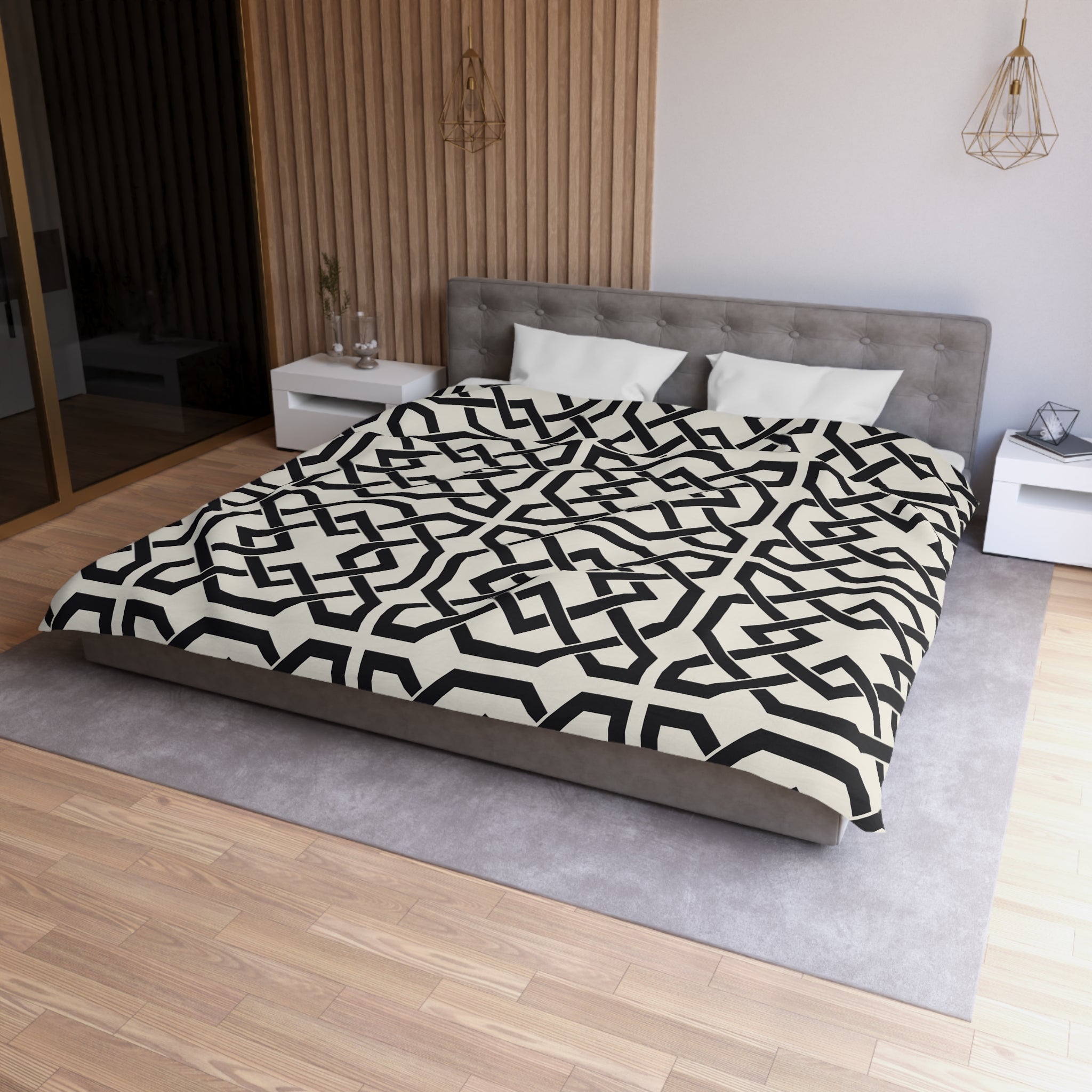 a modern bedroom with a large bed featuring a black and white geometric patterned comforter. The bed is positioned against a wall with a wooden panel, and there are two white nightstands on either side of the bed. The room has a wooden floor and a gray area rug, creating a cohesive and stylish design.