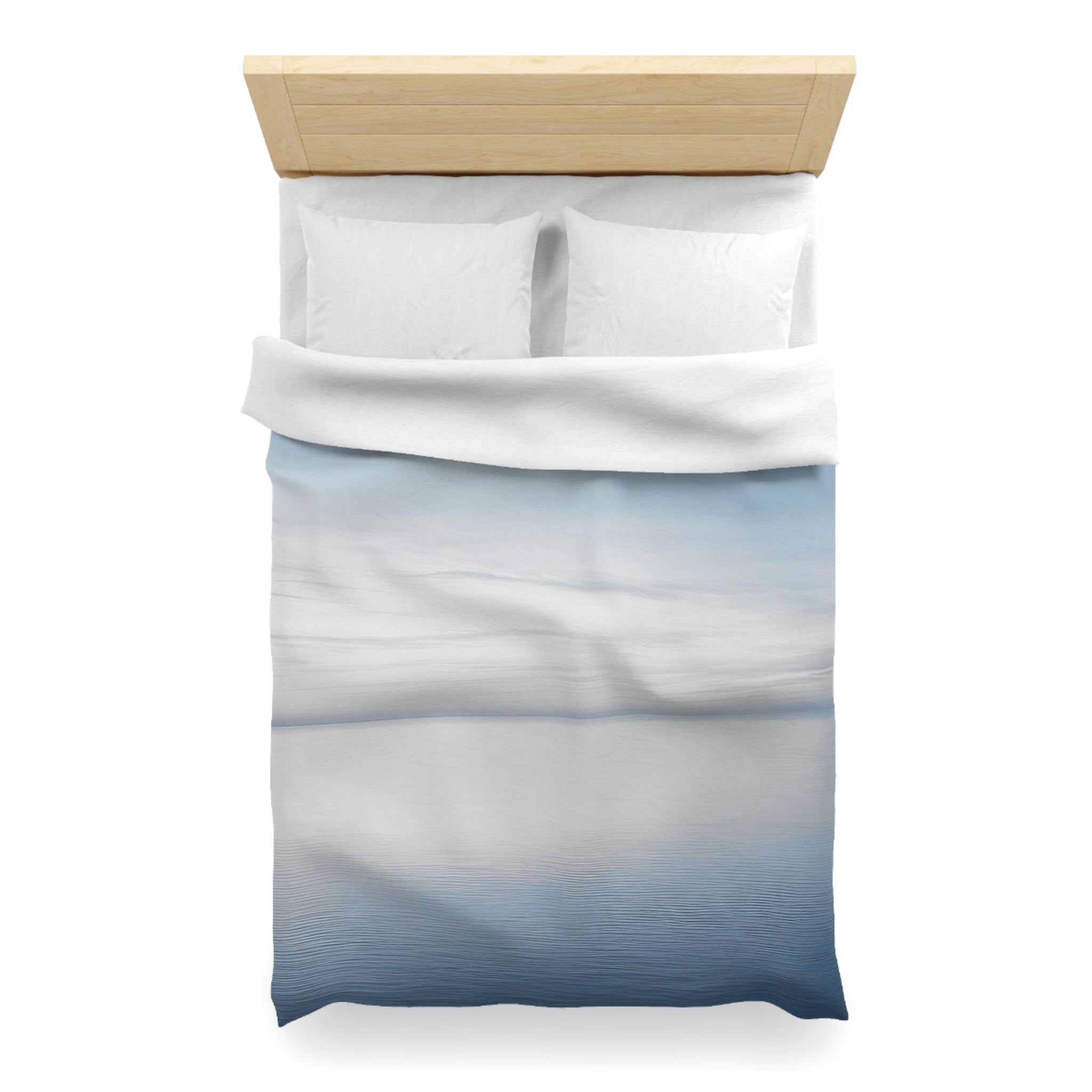 A neatly made bed with a white comforter and pillows, featuring a blue and white gradient design.
