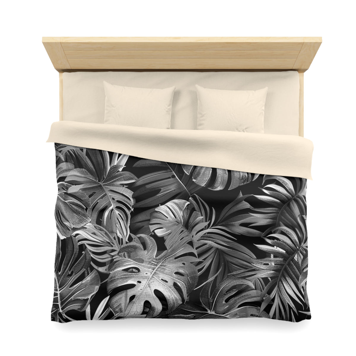 a bed with a black and white tropical leaf pattern on the comforter and pillowcases.