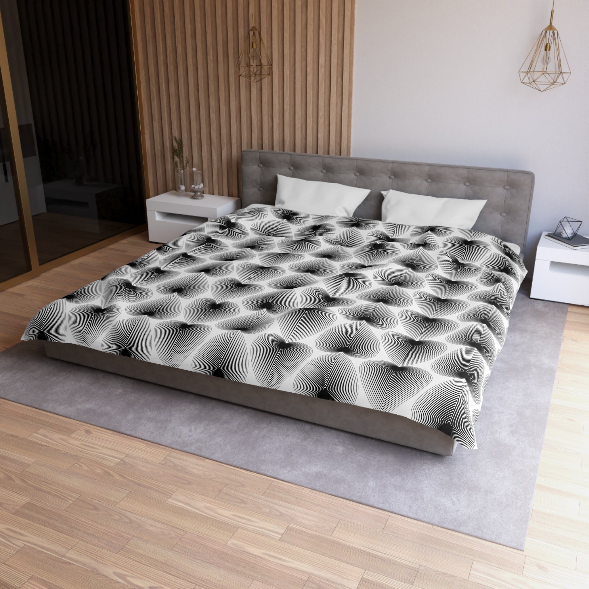 a modern bedroom with a large bed featuring a black and white geometric patterned comforter. The bed is positioned against a wall with a wooden panel, and there are two nightstands on either side of the bed. The room has a wooden floor and a gray area rug, creating a cohesive and stylish interior design.