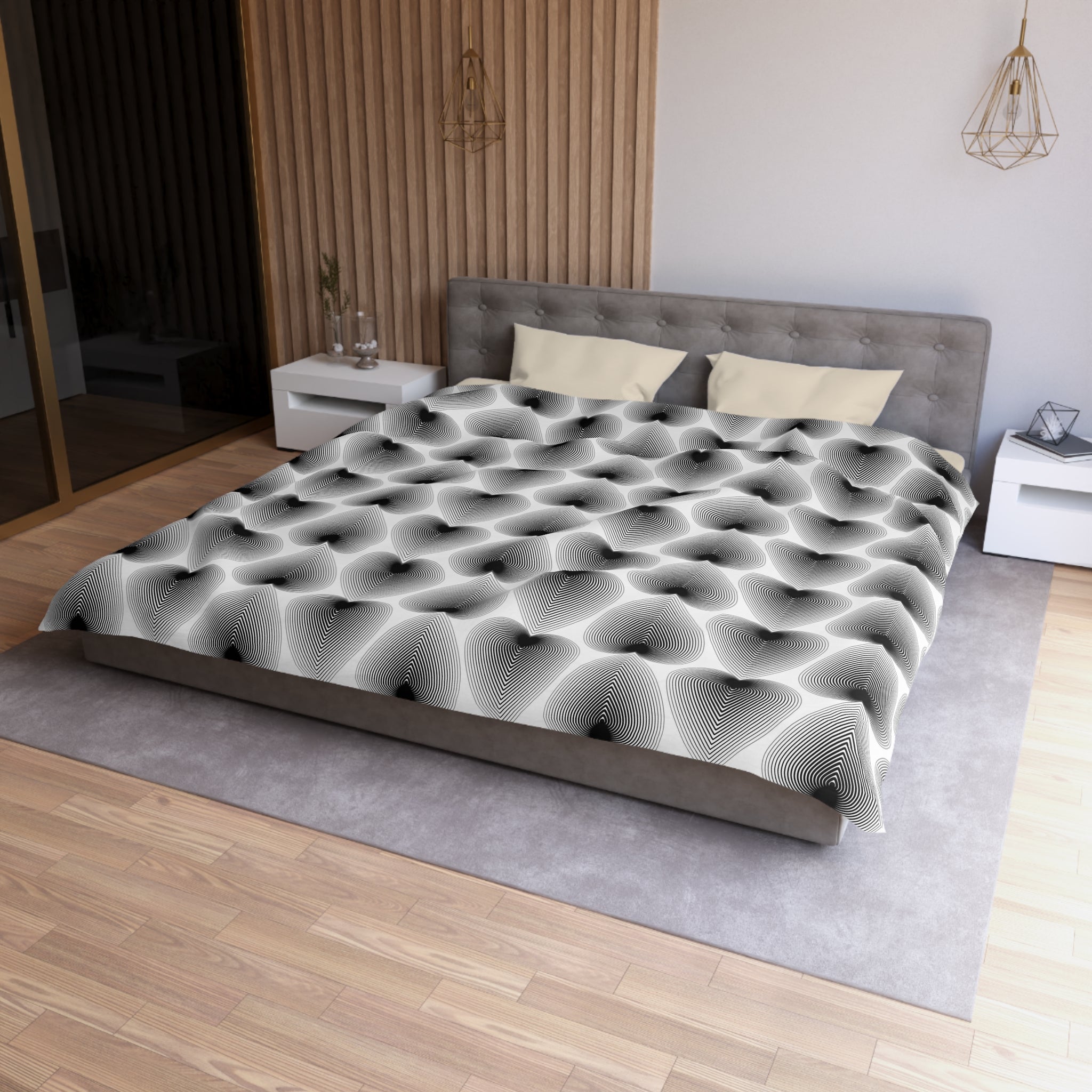 a modern bedroom with a large bed, a gray headboard, and a gray and white patterned comforter. The room has a wooden floor and white walls, creating a clean and minimalist aesthetic.