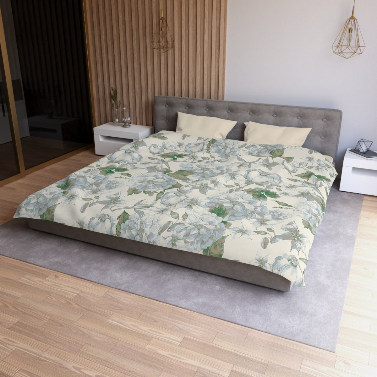a modern bedroom with a large bed, a gray headboard, and a floral patterned comforter. The room has a wooden floor and white walls, creating a serene and elegant atmosphere.