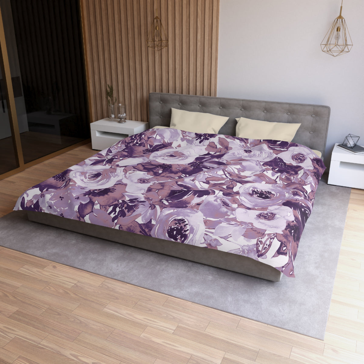 a modern bedroom with a large bed covered in a purple and white floral comforter. The bed is positioned against a wall with a wooden panel. The room also features a nightstand, a pendant light, and a vase on a surface.
