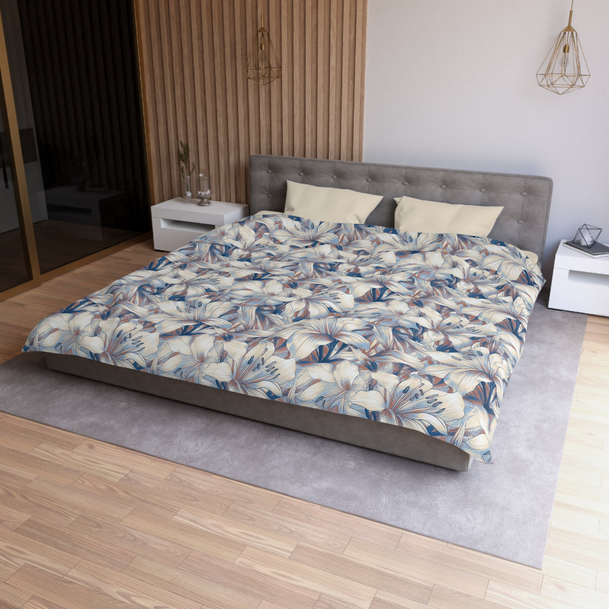 a modern bedroom with a large bed, a gray headboard, and a floral patterned comforter. The room has a wooden floor and white nightstands on either side of the bed. There is a pendant light hanging above the bed, and a vase on one of the nightstands. The overall design and decor of the room create a serene and stylish atmosphere.