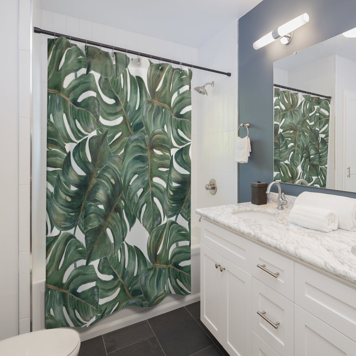 A bathroom with a white vanity, a large shower curtain with a tropical leaf pattern, and a mirror above the sink.