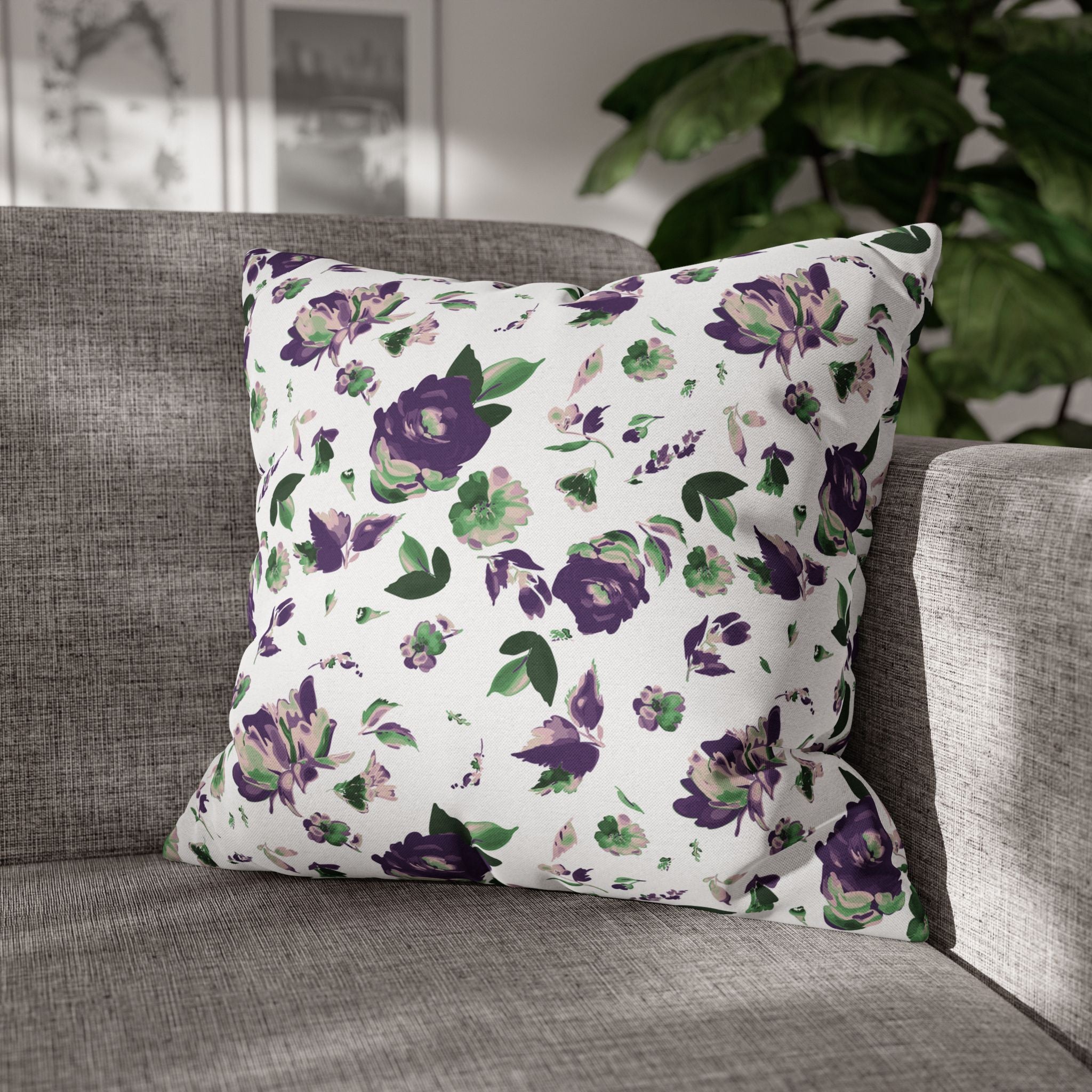 A gray sofa with a white throw pillow featuring a floral pattern in shades of purple and green.