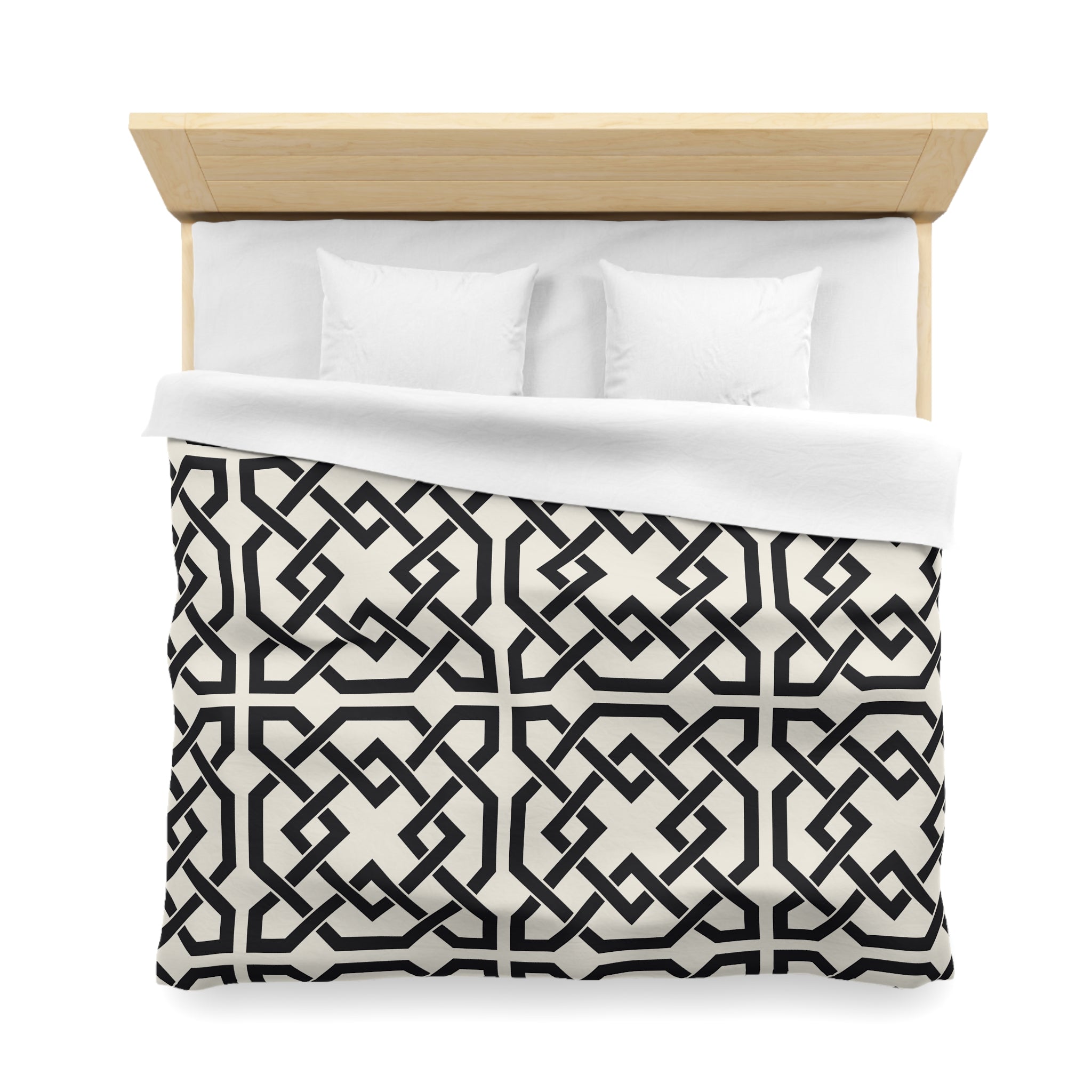 a neatly made bed with a black and white geometric patterned comforter and two white pillows.
