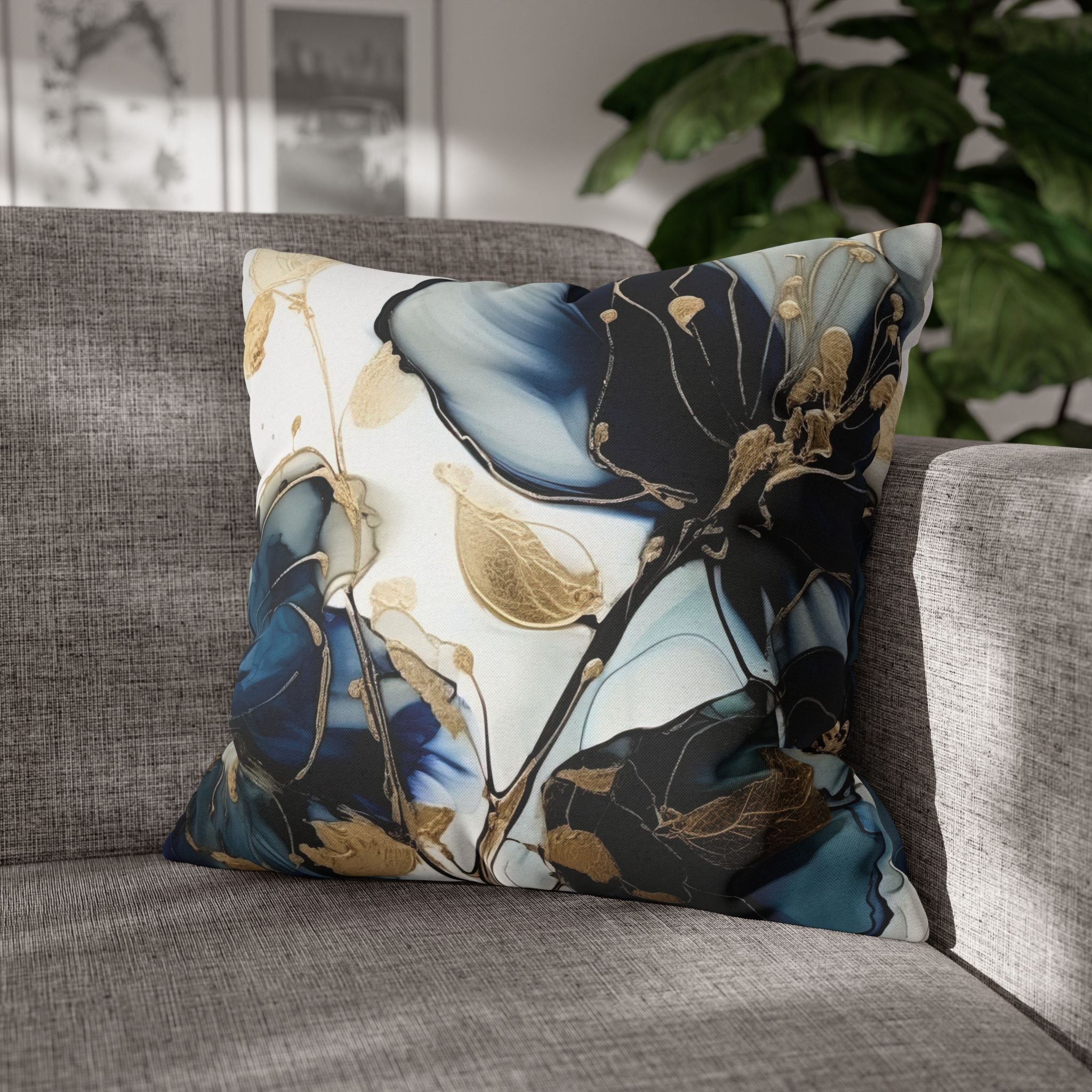 A decorative throw pillow with a floral pattern in shades of blue and gold sits on a gray couch, with a plant visible in the background.