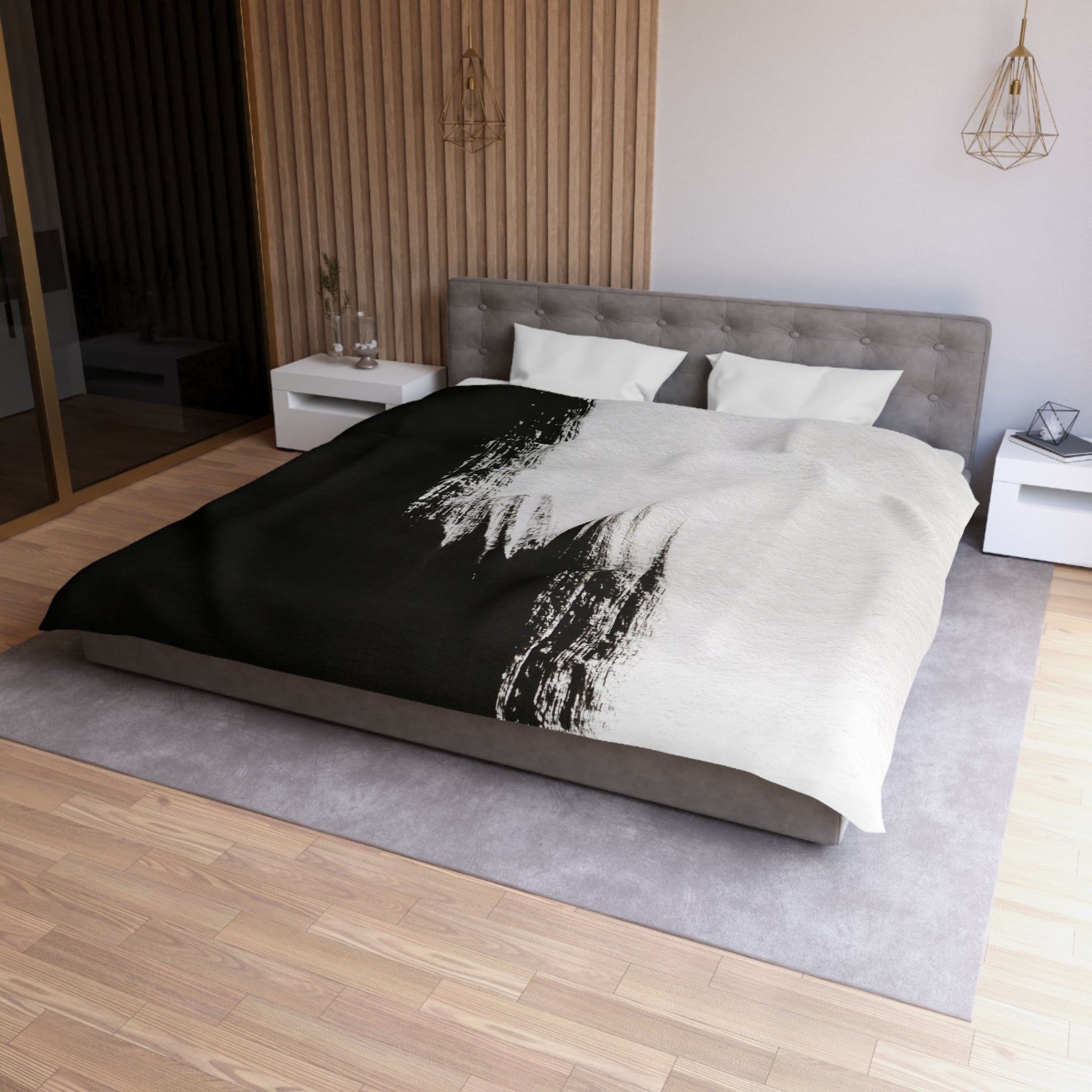 a modern bedroom with a large bed, a gray headboard, and a black and white patterned comforter. The room has a wooden floor and white walls, creating a clean and minimalist aesthetic.