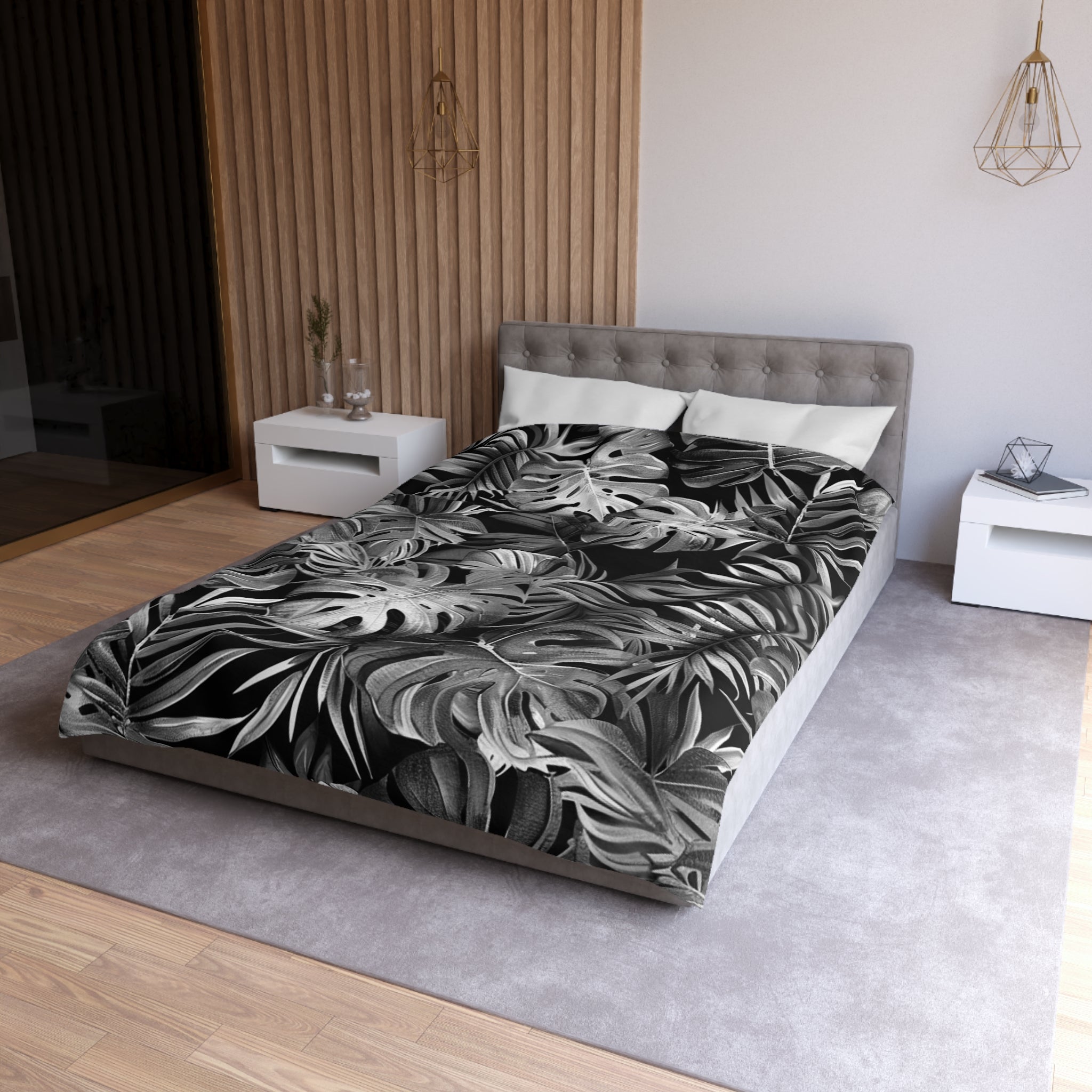 a modern bedroom with a large bed covered in a black and white tropical leaf patterned comforter. The bed is positioned against a wall with a wooden panel design. The room also includes a nightstand and a pendant light fixture, creating a stylish and contemporary atmosphere.