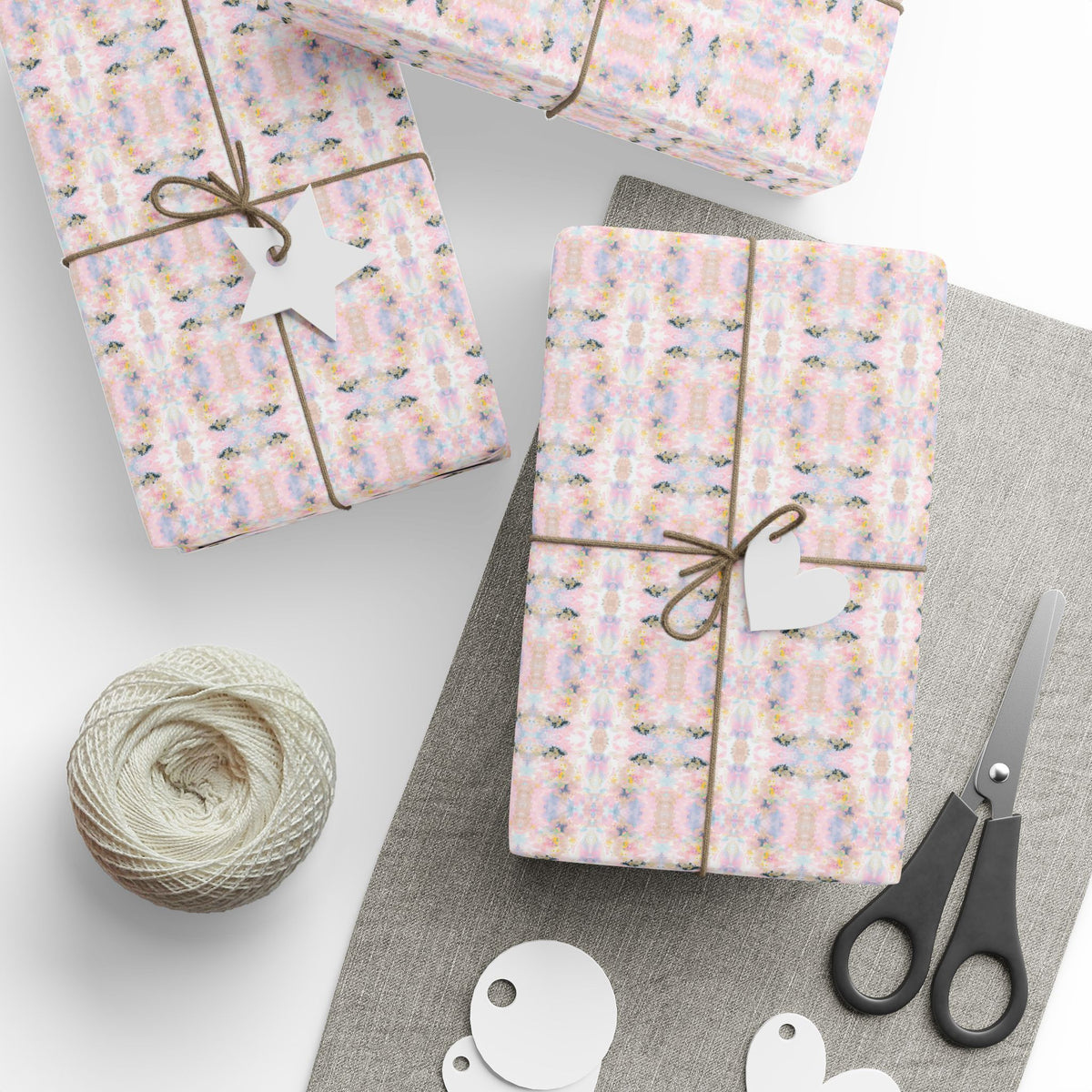 a collection of gift-wrapped presents, a spool of thread, scissors, and tags, all arranged on a gray surface.