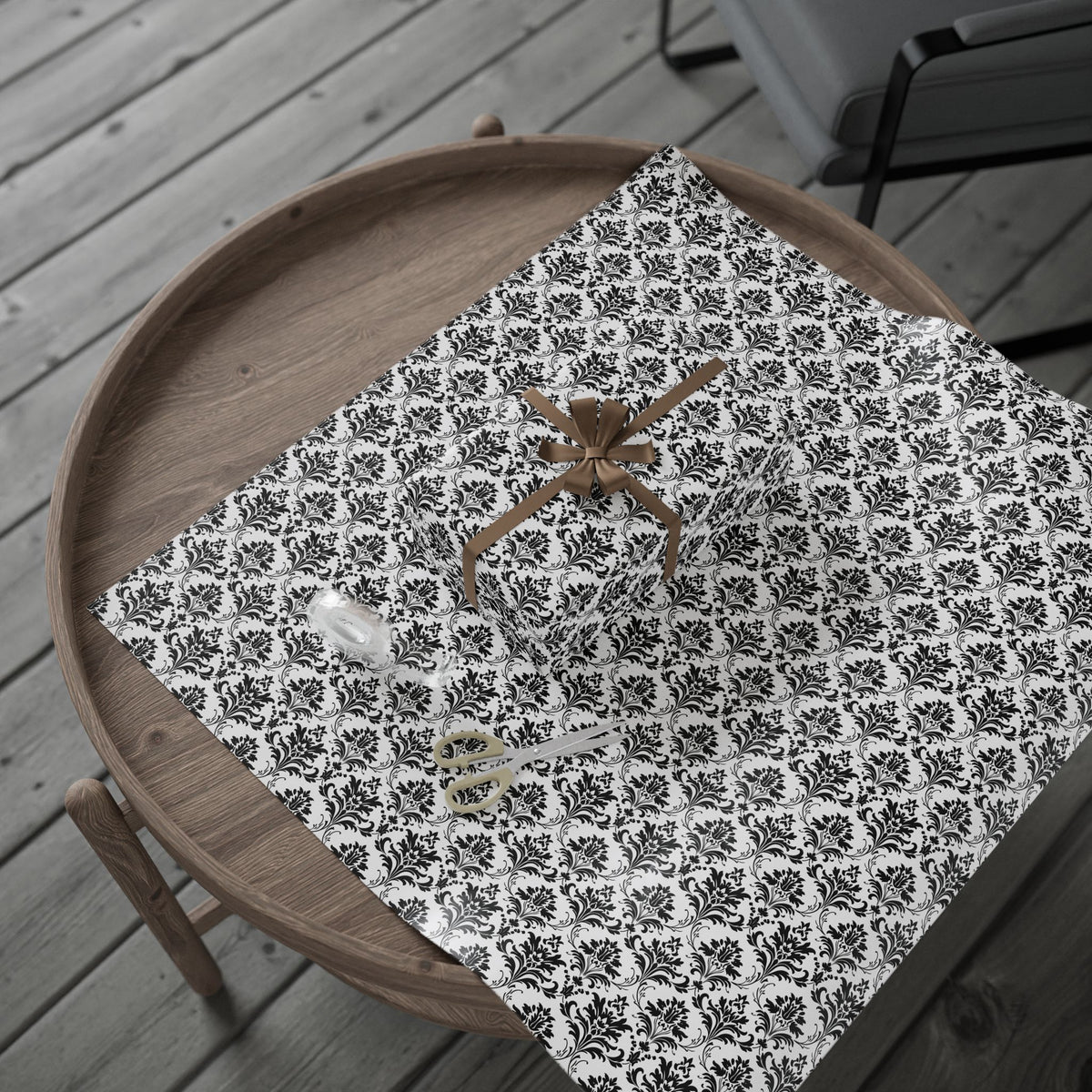 Gift wrapped in classic black and white damask wrapping paper with a roll on a round wooden side table