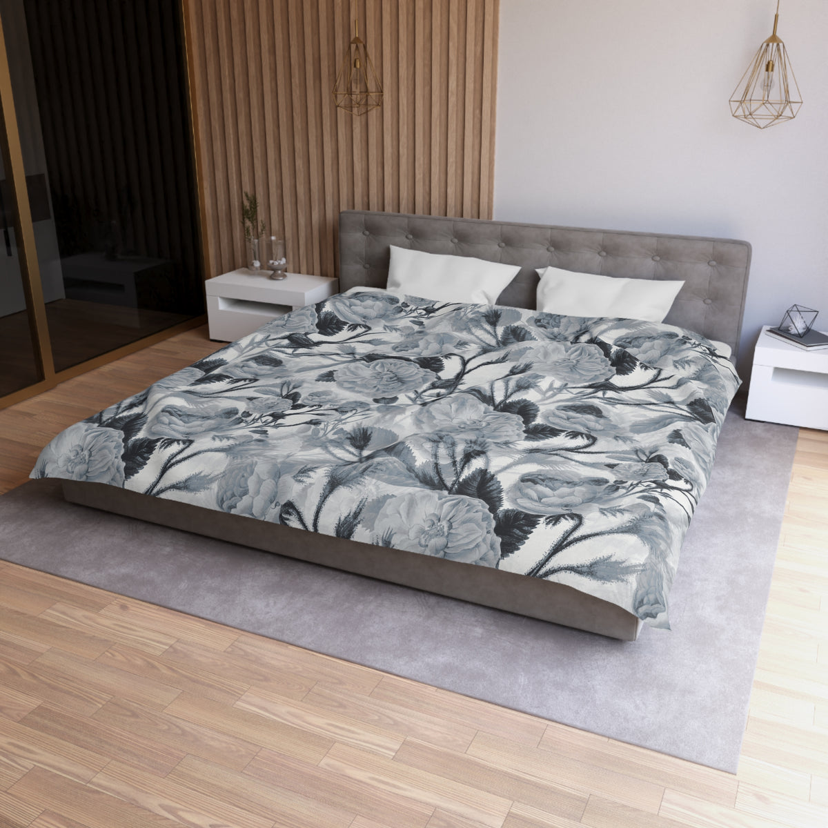 a modern bedroom with a large bed covered in a gray and white floral comforter. The bed is positioned against a wall with a wooden paneling. The room also features a nightstand, a pendant light, and a rug on the floor.