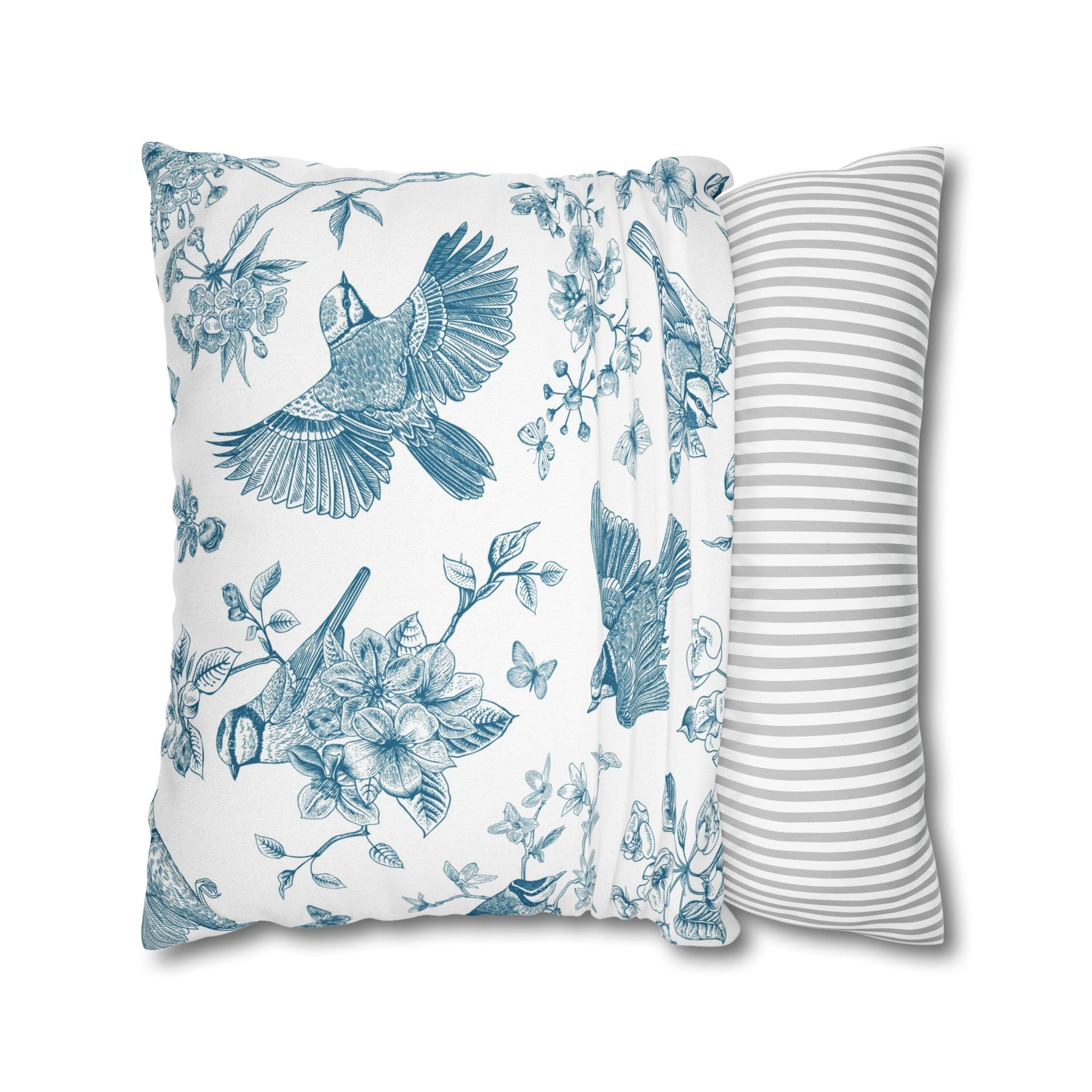a decorative pillow with a floral and bird motif, including a blue bird in flight and various flowers and leaves.