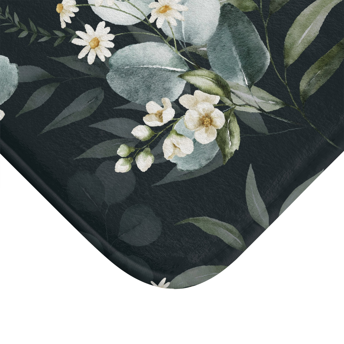 a close-up view of a black surface with a floral pattern of white flowers and green leaves.
