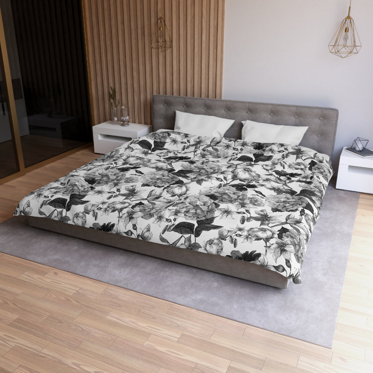 a modern bedroom with a large bed, a gray headboard, and a floral print comforter. The room has a wooden floor and white walls, creating a clean and minimalist aesthetic.