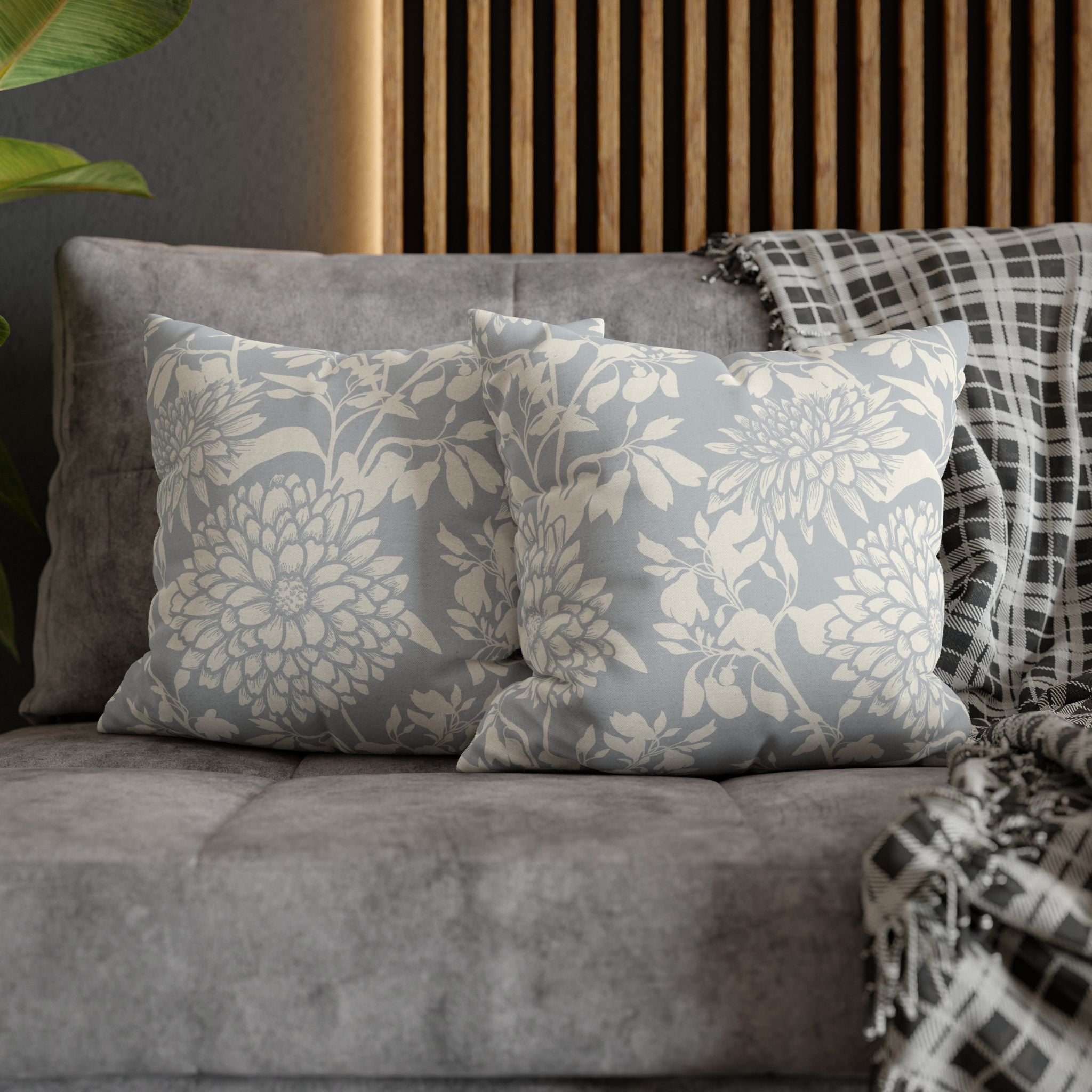 a gray sofa with two gray and white patterned throw pillows resting on it. The pillows have a floral design.
