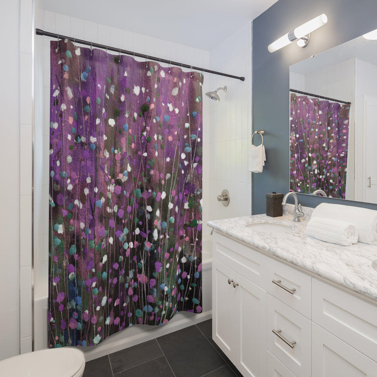 A modern bathroom with a white vanity, a shower curtain with a purple and green floral pattern, and a mirror above the vanity.