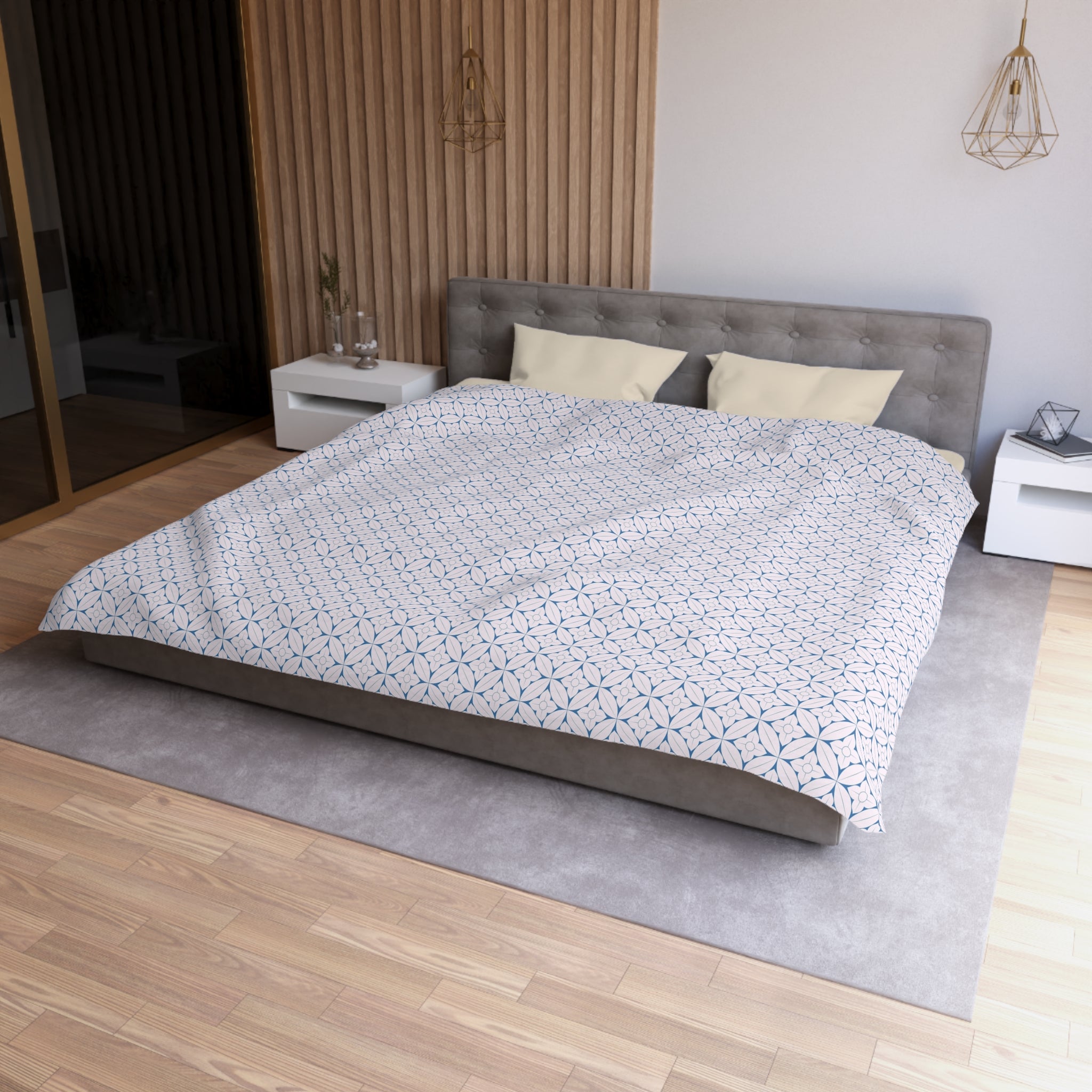 a modern bedroom with a large bed, a gray headboard, and a wooden floor. The bed is covered in a patterned comforter and has two pillows. There are two nightstands on either side of the bed, and a rug is placed in front of the bed. The room has a minimalist and clean design, with a focus on the bed and its surroundings.