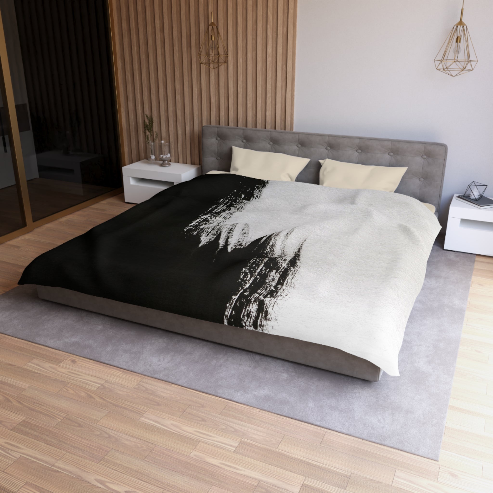 a modern bedroom with a large bed, a gray headboard, and a black and white patterned comforter. The room has a wooden floor and white walls, creating a clean and minimalist aesthetic.