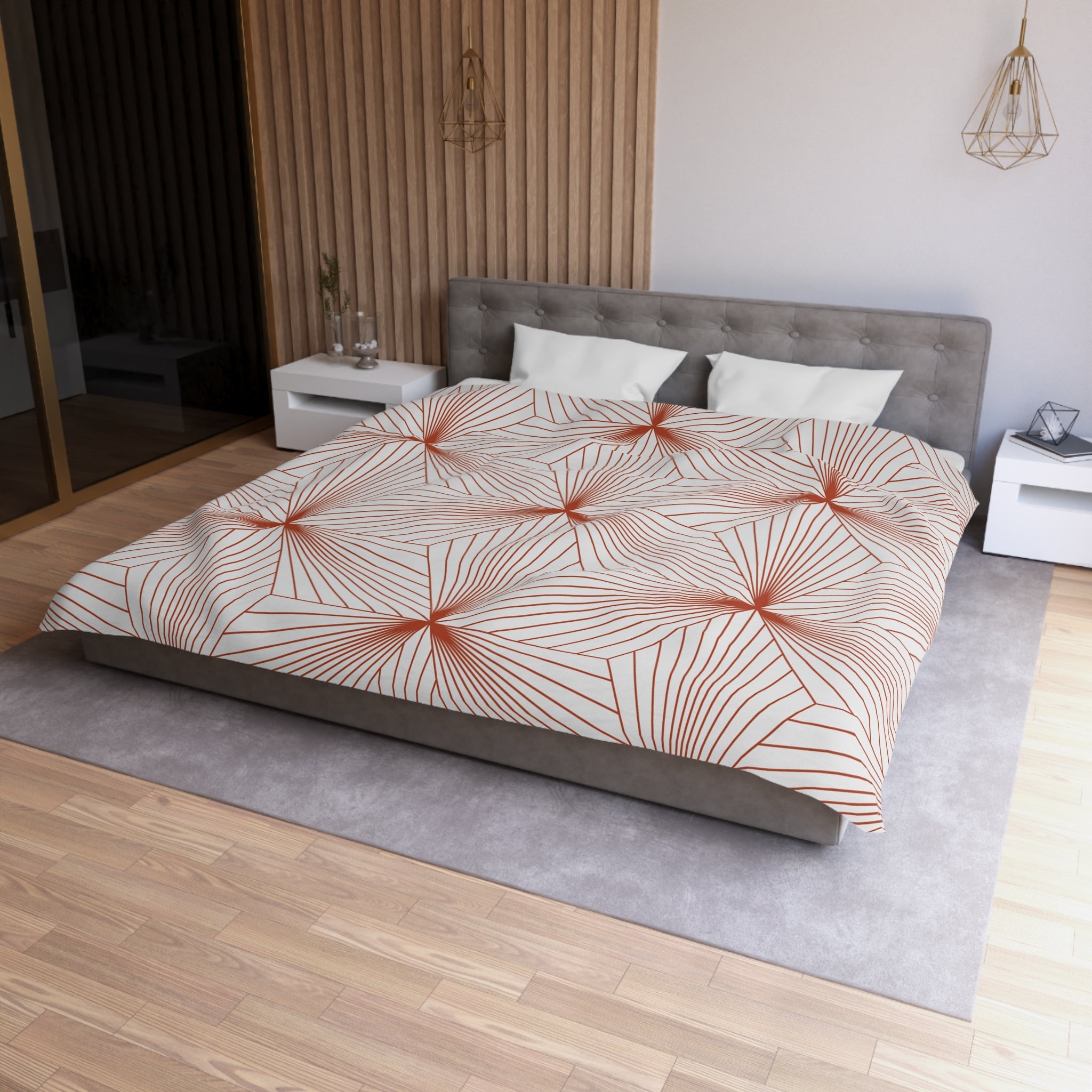 a modern bedroom with a large bed, a gray headboard, and a patterned comforter. The room has a wooden floor and white walls, creating a clean and minimalist aesthetic.