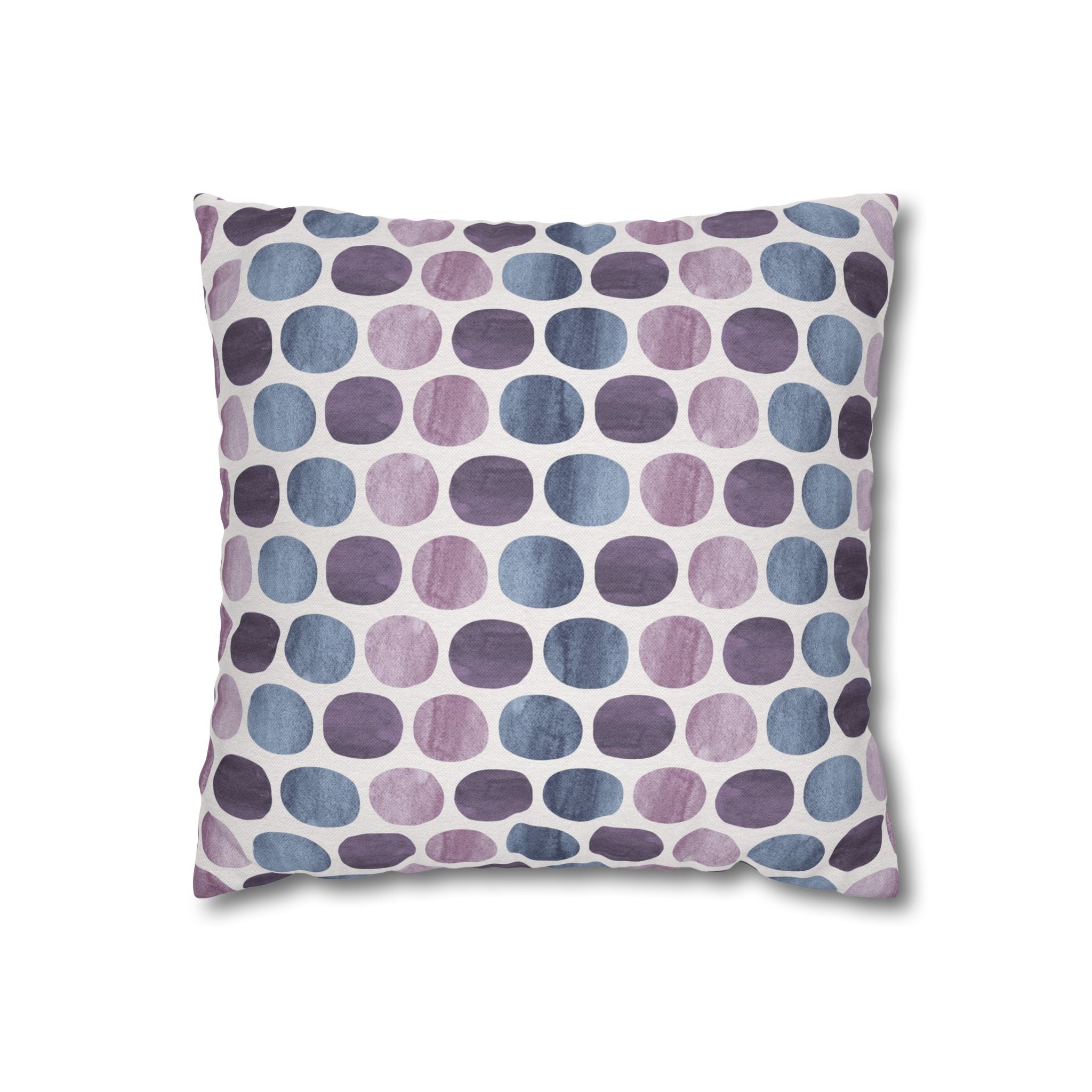 a square throw pillow with a repeating pattern of purple and blue dots on a white background.