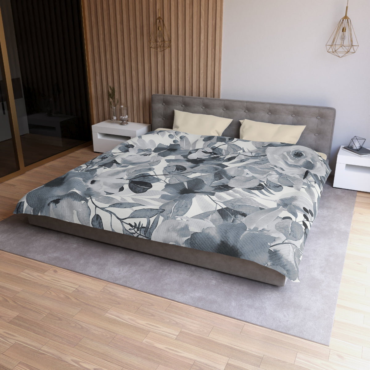 a modern bedroom with a large bed, a gray headboard, and a gray and white floral comforter. The room has a wooden floor and white walls, creating a serene and elegant atmosphere.