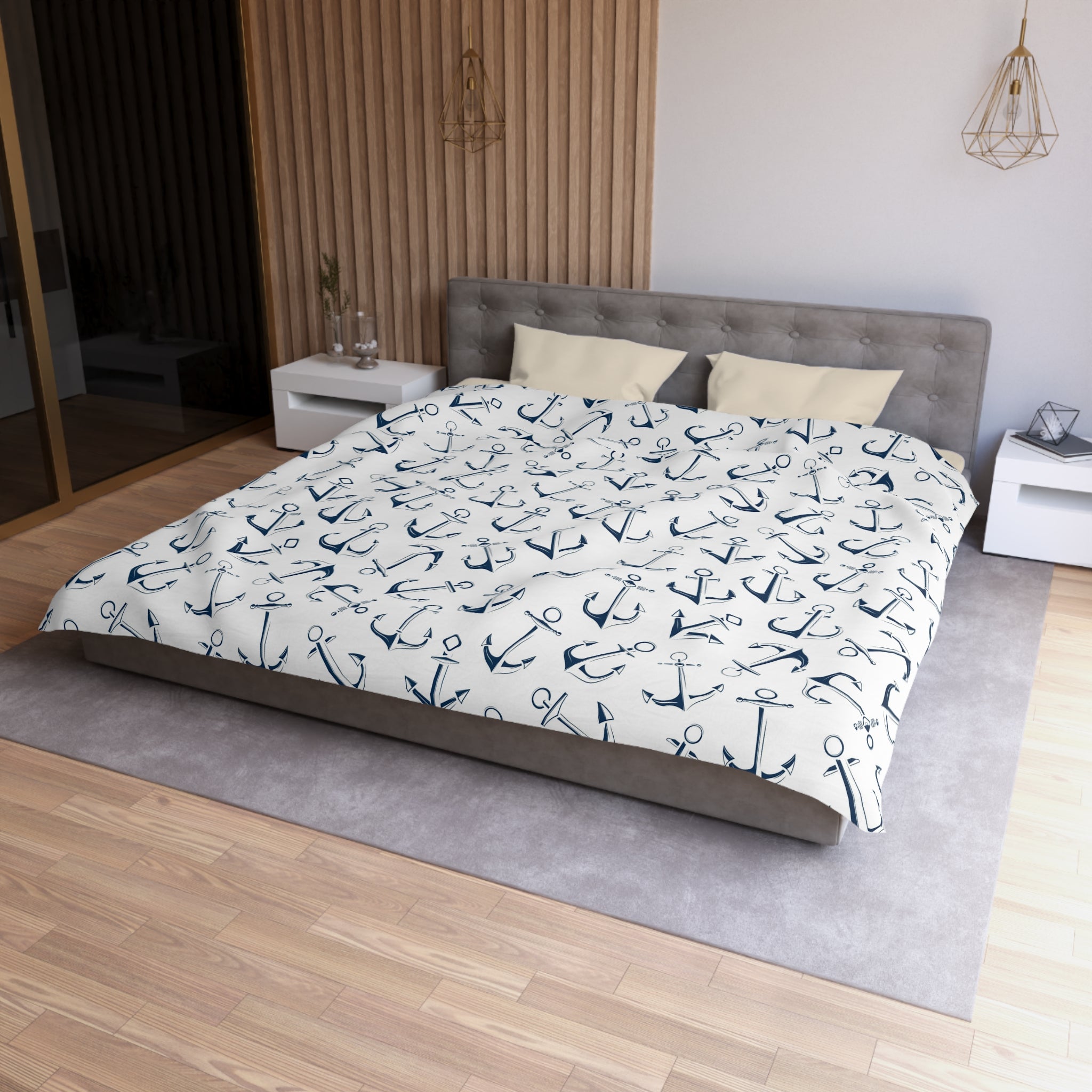 a bedroom with a large bed covered in a white and navy blue anchor-patterned comforter. The bed is positioned against a wall with a wooden panel. There are two nightstands on either side of the bed, and a rug is placed in front of the bed.