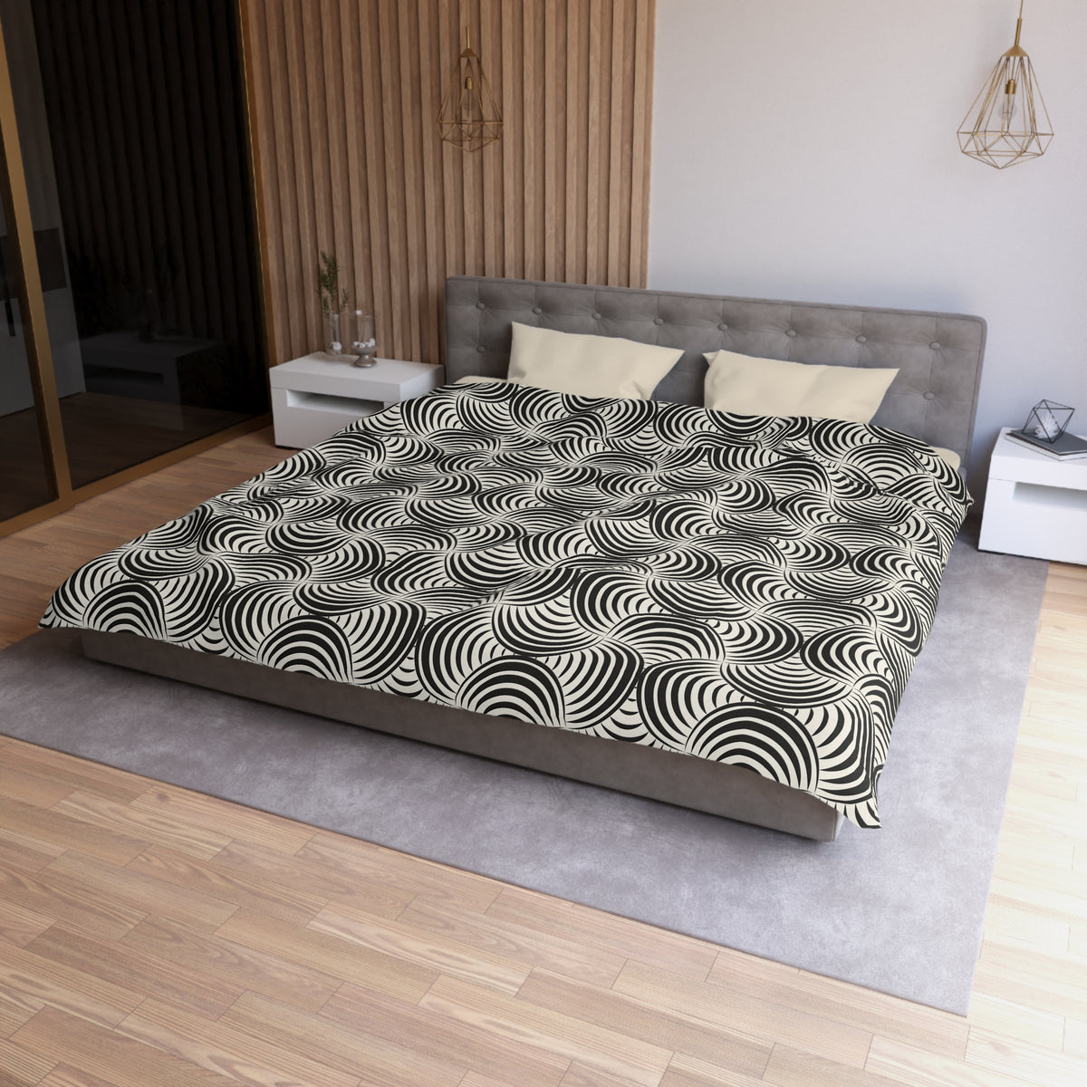 a modern bedroom with a large bed, a gray headboard, and a black and white patterned comforter. The room has a wooden floor and white walls, creating a clean and minimalist aesthetic.