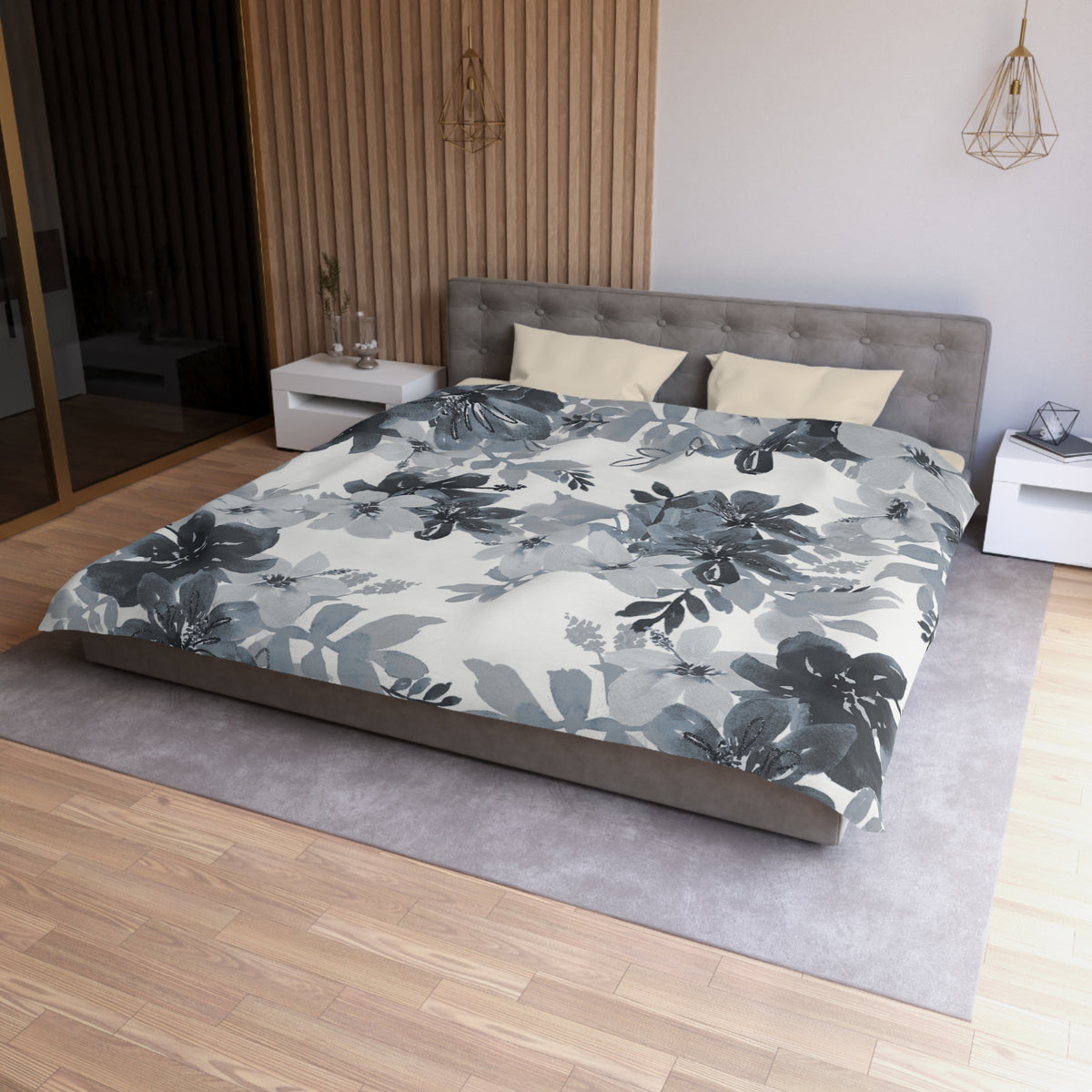 a modern bedroom with a large bed, a gray headboard, and a gray and white floral comforter. The room has a wooden floor and white walls, creating a serene and elegant atmosphere.