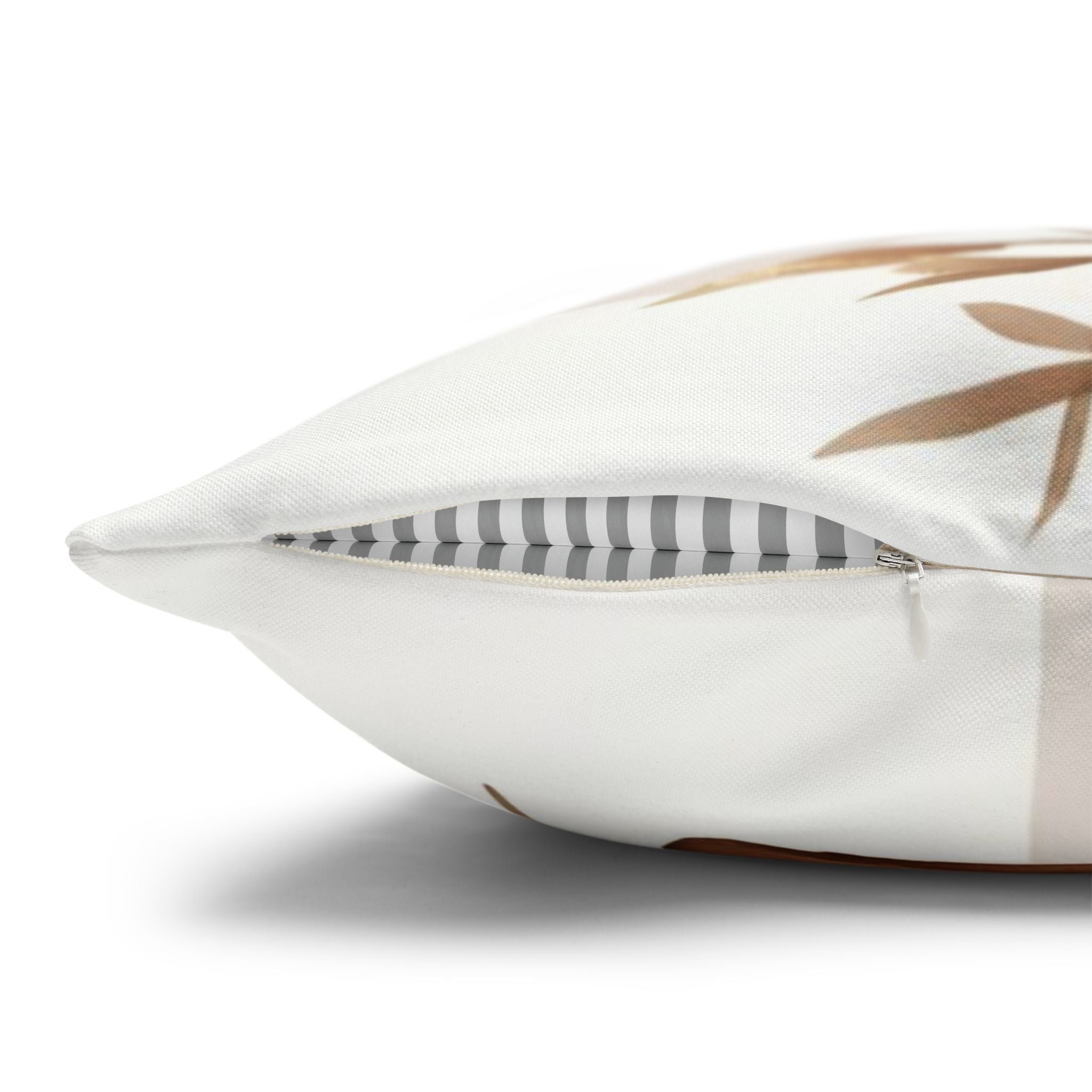 a close-up view of a white pillow with a brown leaf pattern on it.