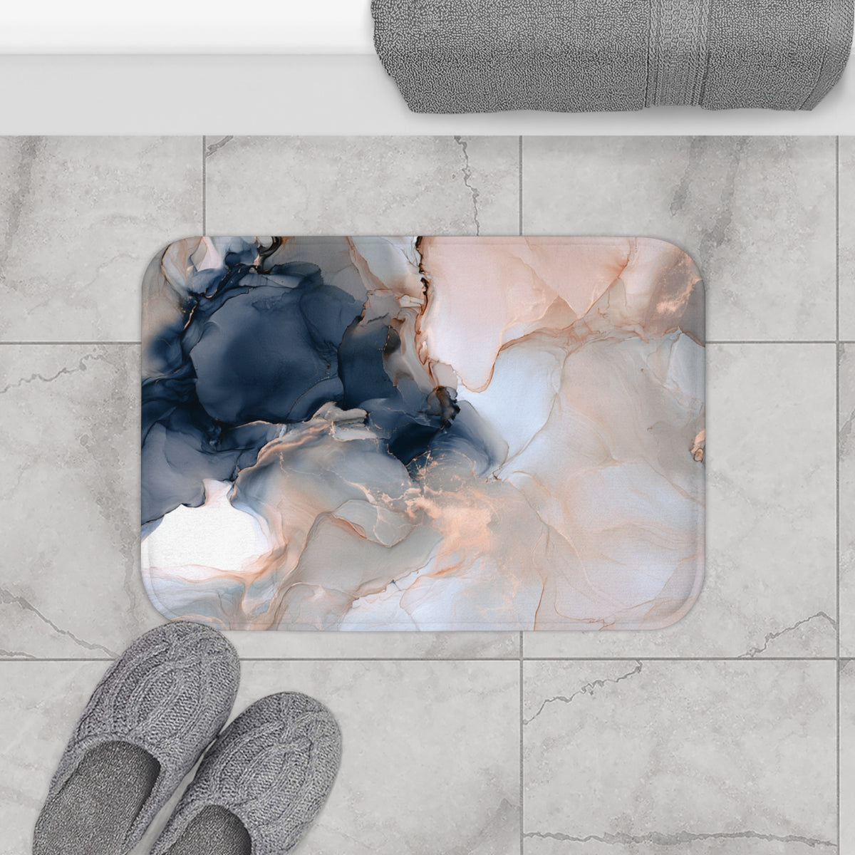 a bathroom floor with a marble-like pattern, a pair of gray slippers, and a rolled-up gray towel.