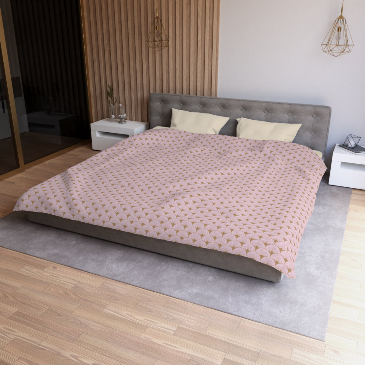 a modern bedroom with a large bed, a gray headboard, and a pink and gold patterned comforter. The room has a wooden floor and white walls, creating a clean and minimalist aesthetic.