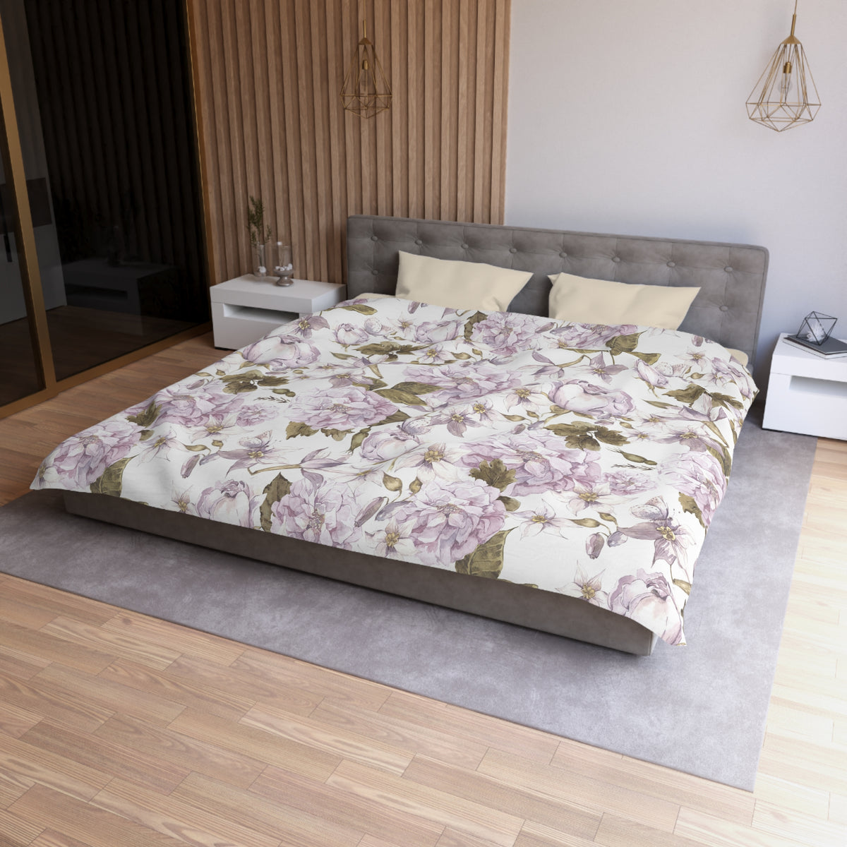 a modern bedroom with a large bed, a gray headboard, and a floral bedspread. The room has a wooden floor and white walls, creating a serene and elegant atmosphere.