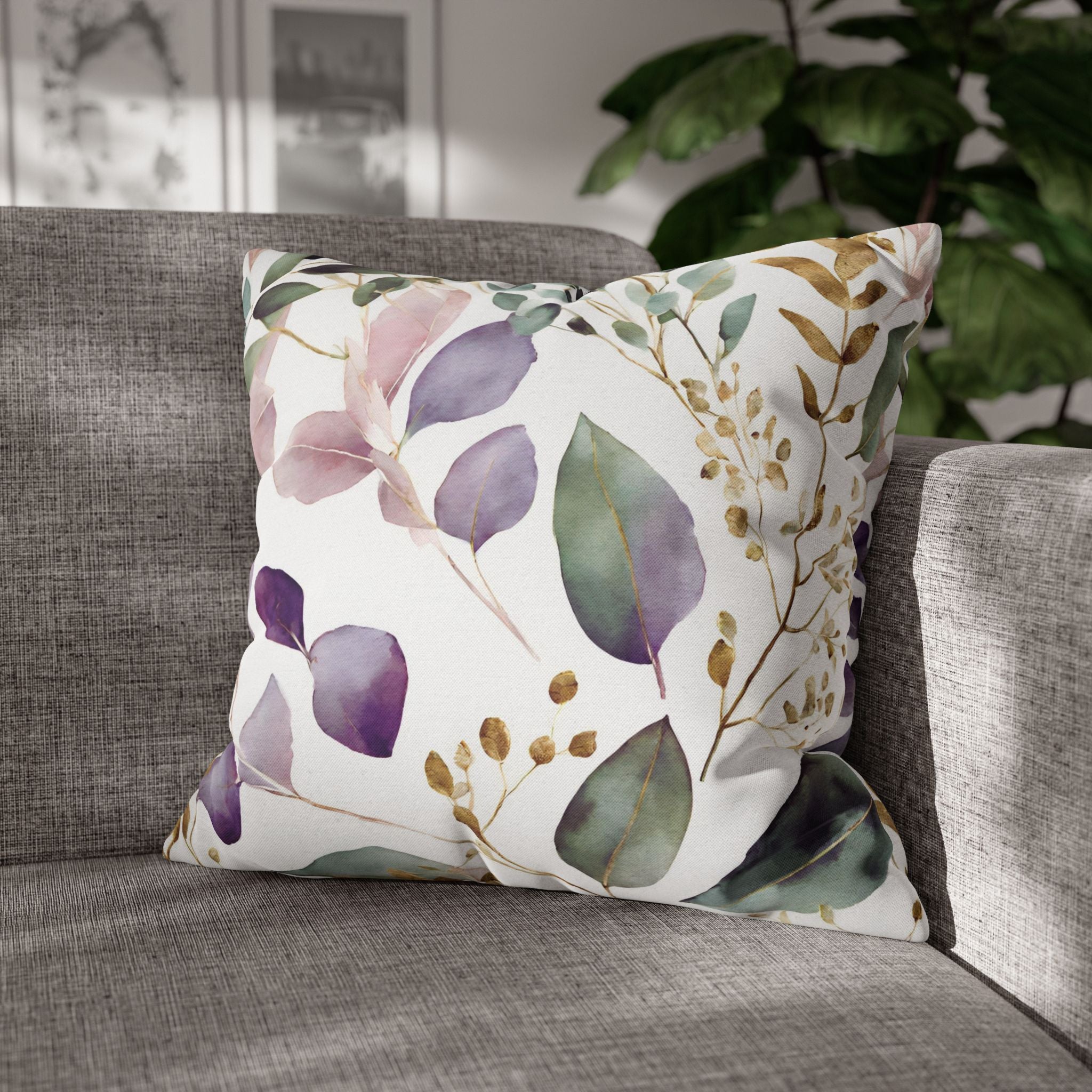 A gray sofa with a decorative throw pillow featuring a floral pattern in shades of purple, green, and gold.