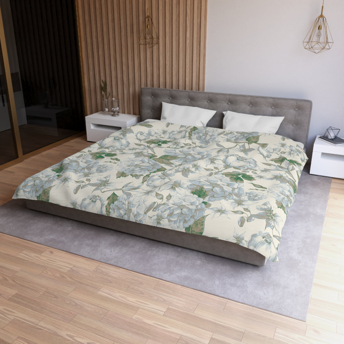 a modern bedroom with a large bed, a gray headboard, and a floral patterned comforter. The room has a wooden floor and white walls, creating a serene and elegant atmosphere.