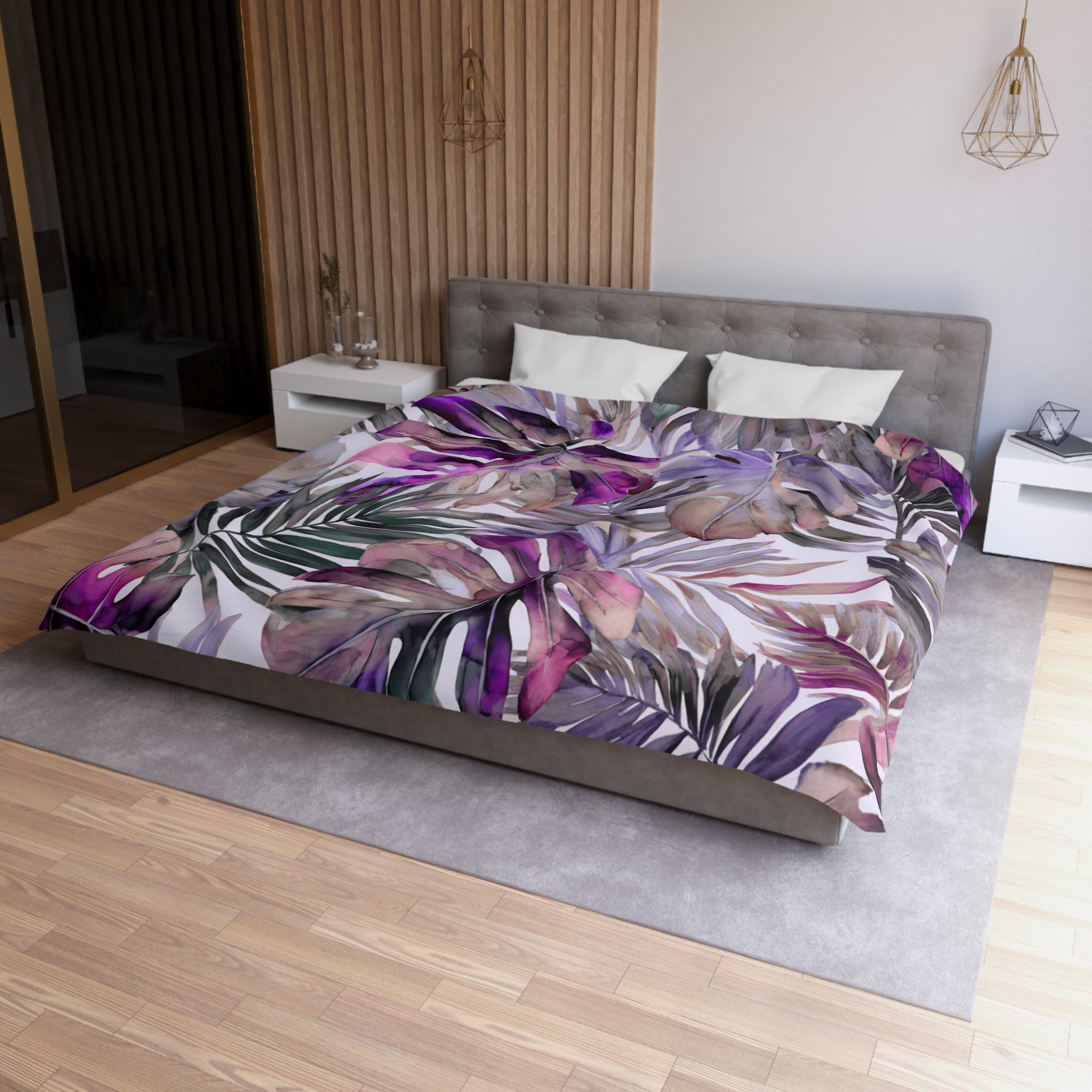 a modern bedroom with a large bed covered in a colorful, tropical-themed comforter featuring palm leaves and other vibrant patterns. The bed is positioned against a wall with a wooden panel, and there are two nightstands on either side of the bed. The room has a minimalist and stylish design, with a gray headboard and a wooden floor.