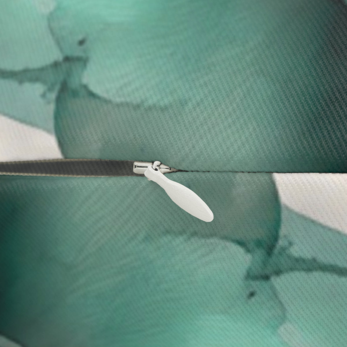 a close-up view of a white zipper attached to a fabric surface, with a blurred green background.
