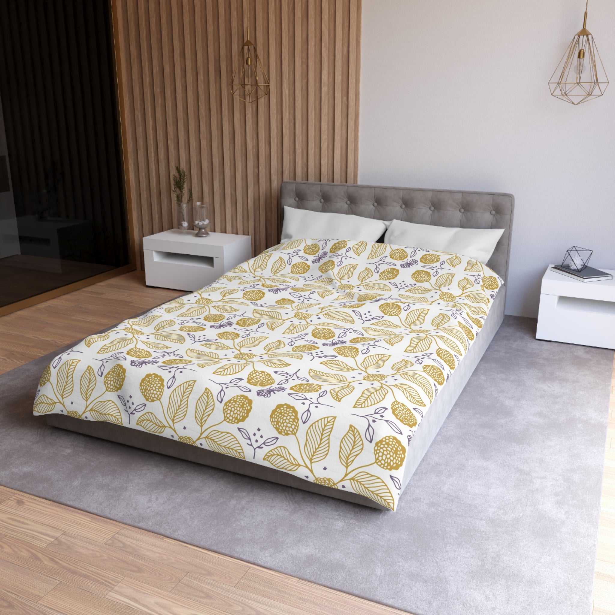 a modern bedroom with a large bed, a gray headboard, and a white nightstand on the left side. The bed is covered in a comforter with a leaf pattern in shades of yellow and white. The room has a neutral color scheme with wooden paneling on the walls and a gray carpet on the floor.
