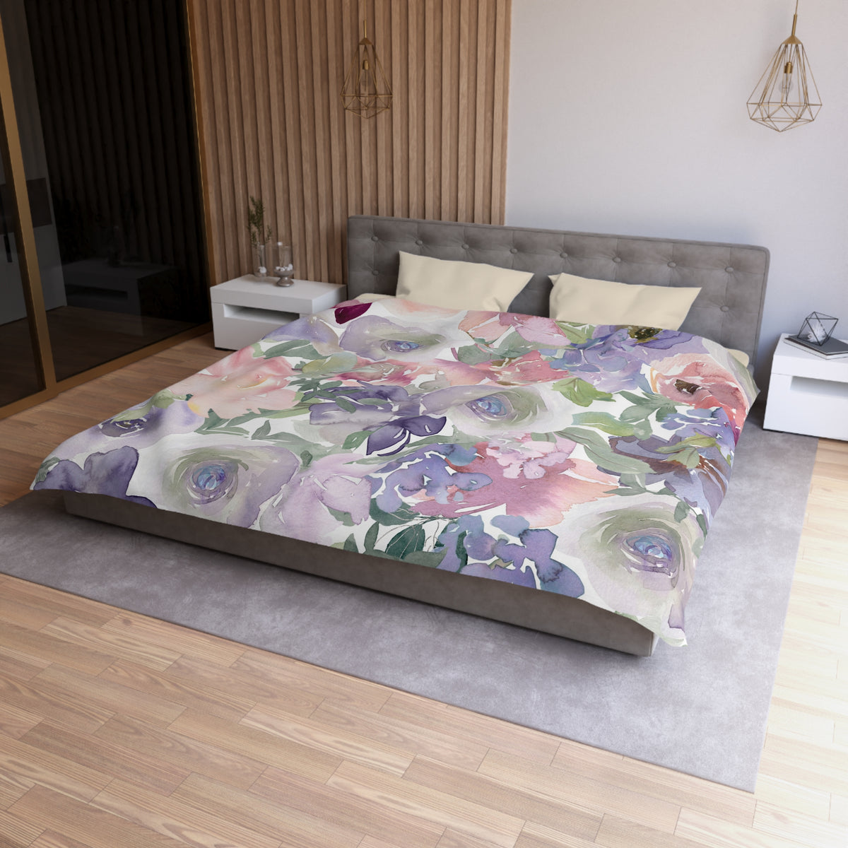 a bedroom with a large bed covered in a colorful floral comforter. The bed is positioned against a wall with a wooden panel. The room also features a nightstand, a pendant light, and a vase on a surface.