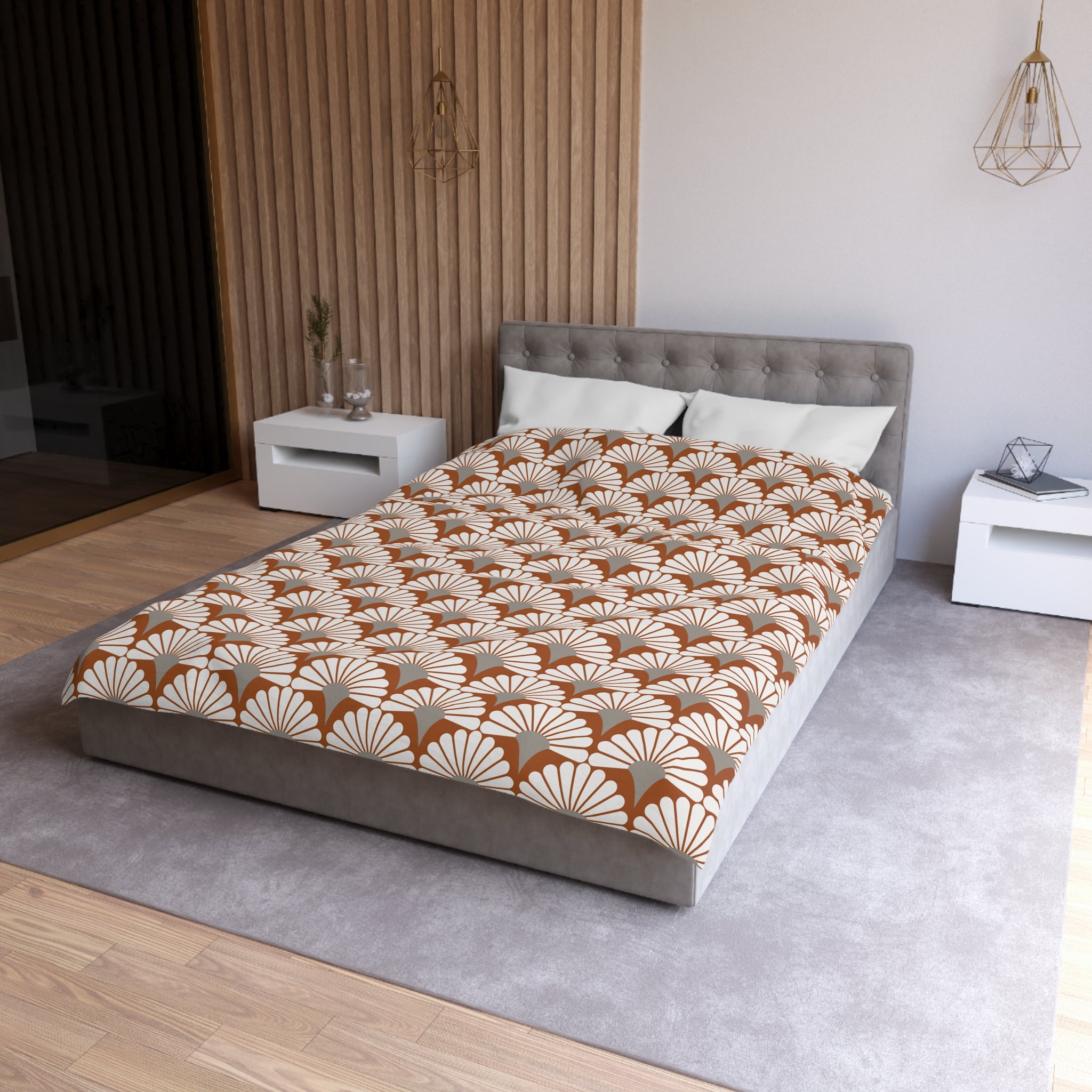 a modern bedroom with a large bed, a gray headboard, and a patterned comforter. The room has a neutral color scheme with a gray carpet and white walls. There are two nightstands on either side of the bed, and a pendant light hangs above the bed.