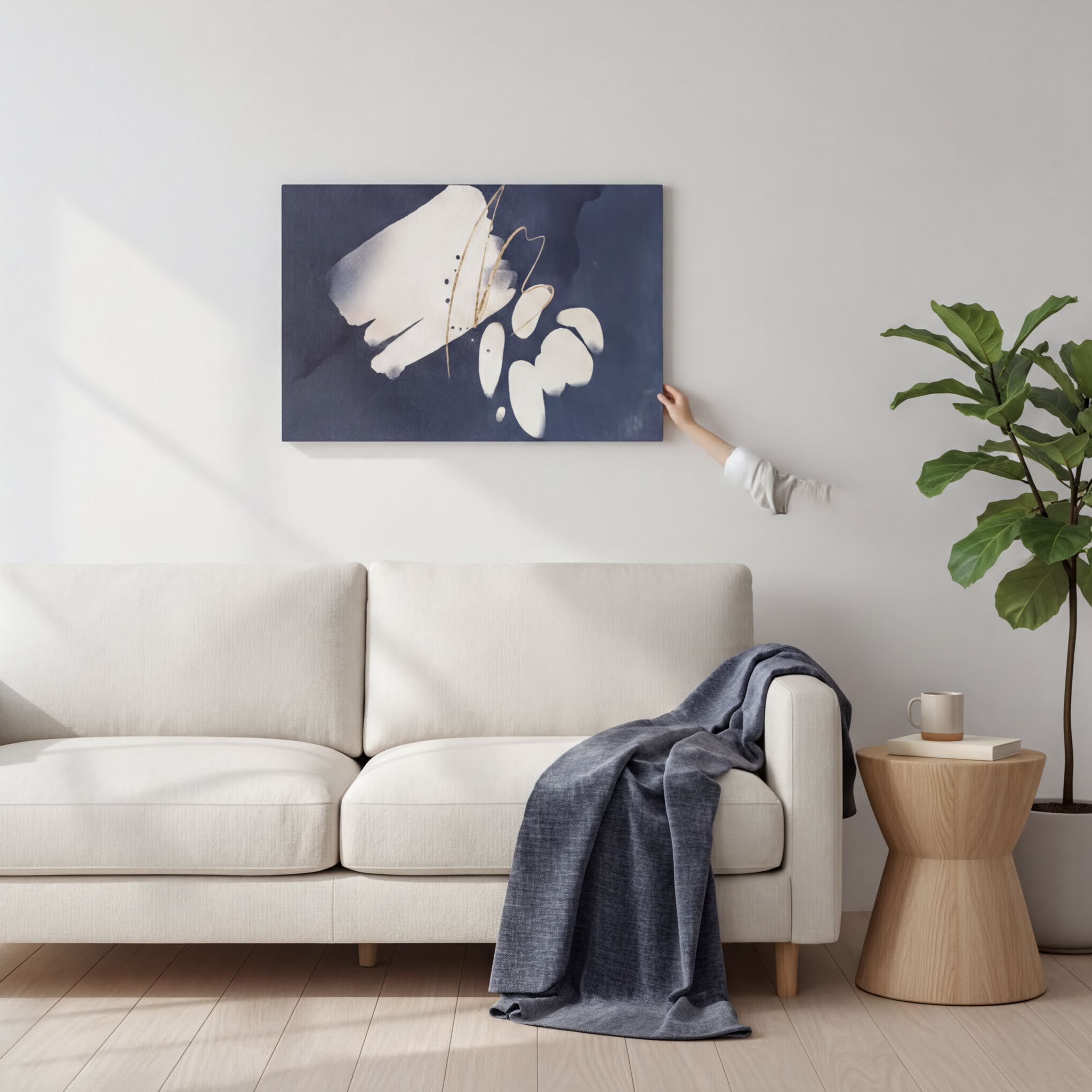 a living room with a white sofa, a wooden side table, and a potted plant. A person's hand is reaching towards a large abstract painting hanging on the wall above the sofa.