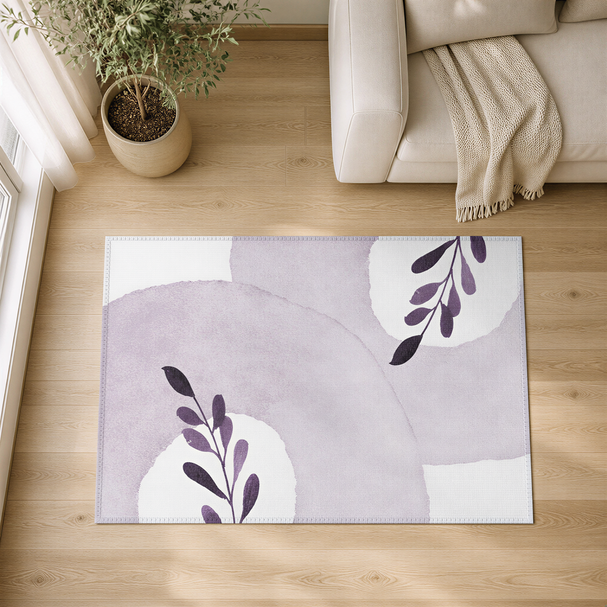 a living room with a large rug on the wooden floor, a white sofa, and a potted plant.