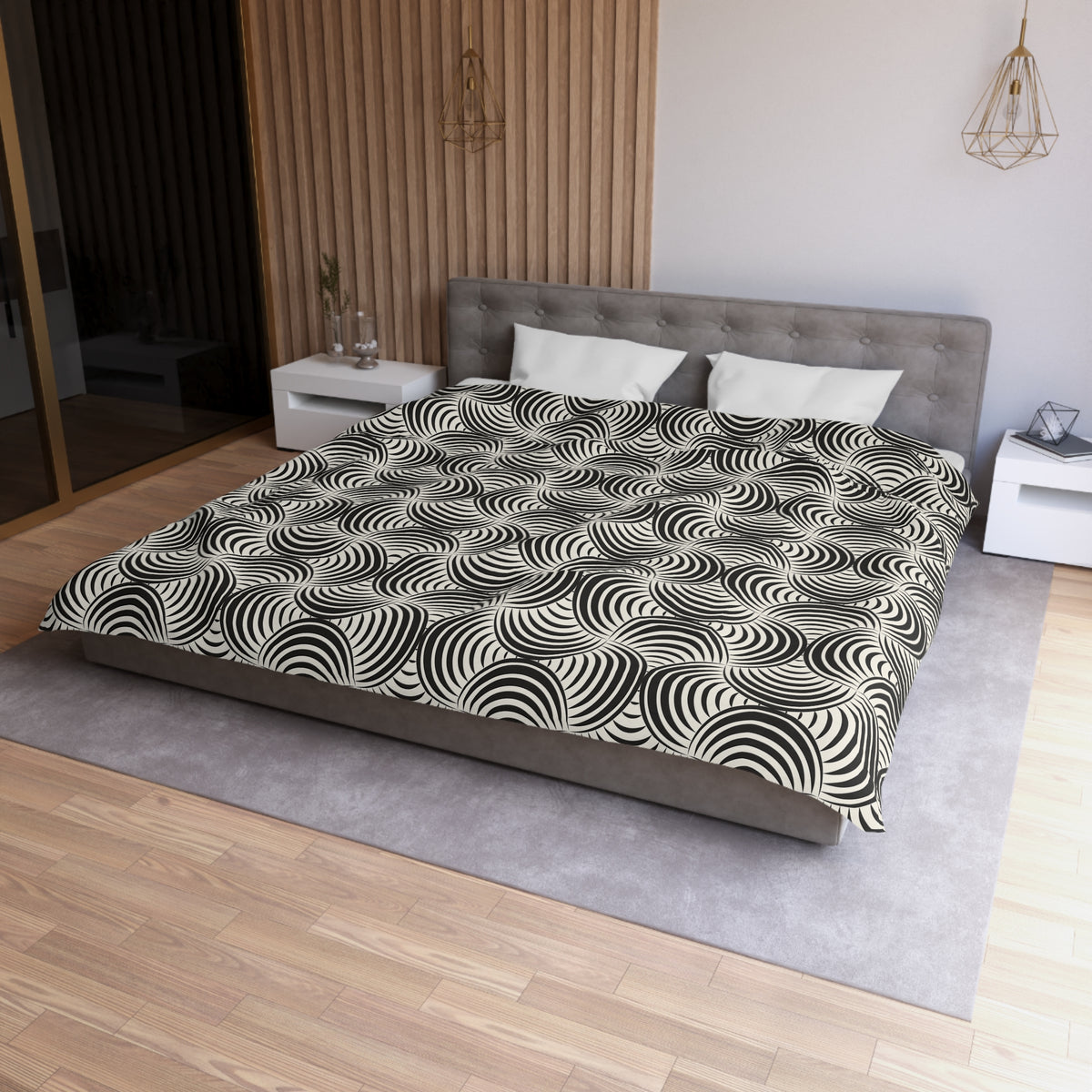 a modern bedroom with a large bed, a gray headboard, and a black and white patterned comforter. The room has a wooden floor and white walls, creating a clean and minimalist aesthetic.
