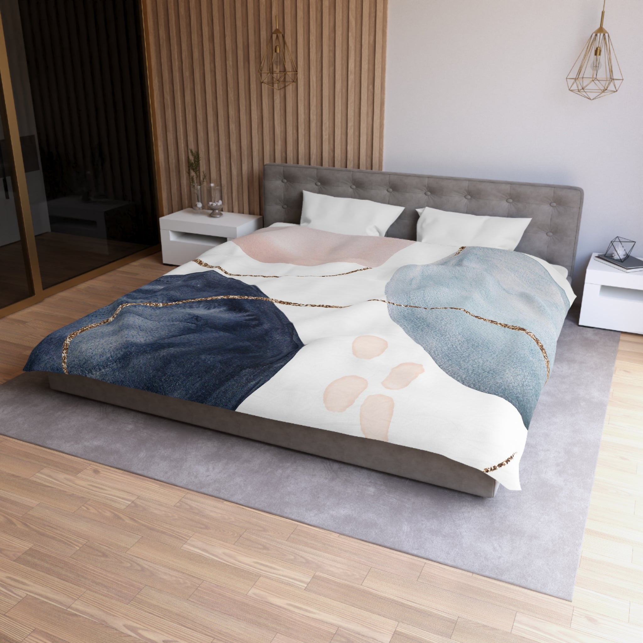 a modern bedroom with a large bed, a gray headboard, and a wooden floor. The bed is covered with a colorful, abstract-patterned comforter featuring blue, white, and pink colors. There are also two nightstands on either side of the bed, and a pendant light hanging above it.