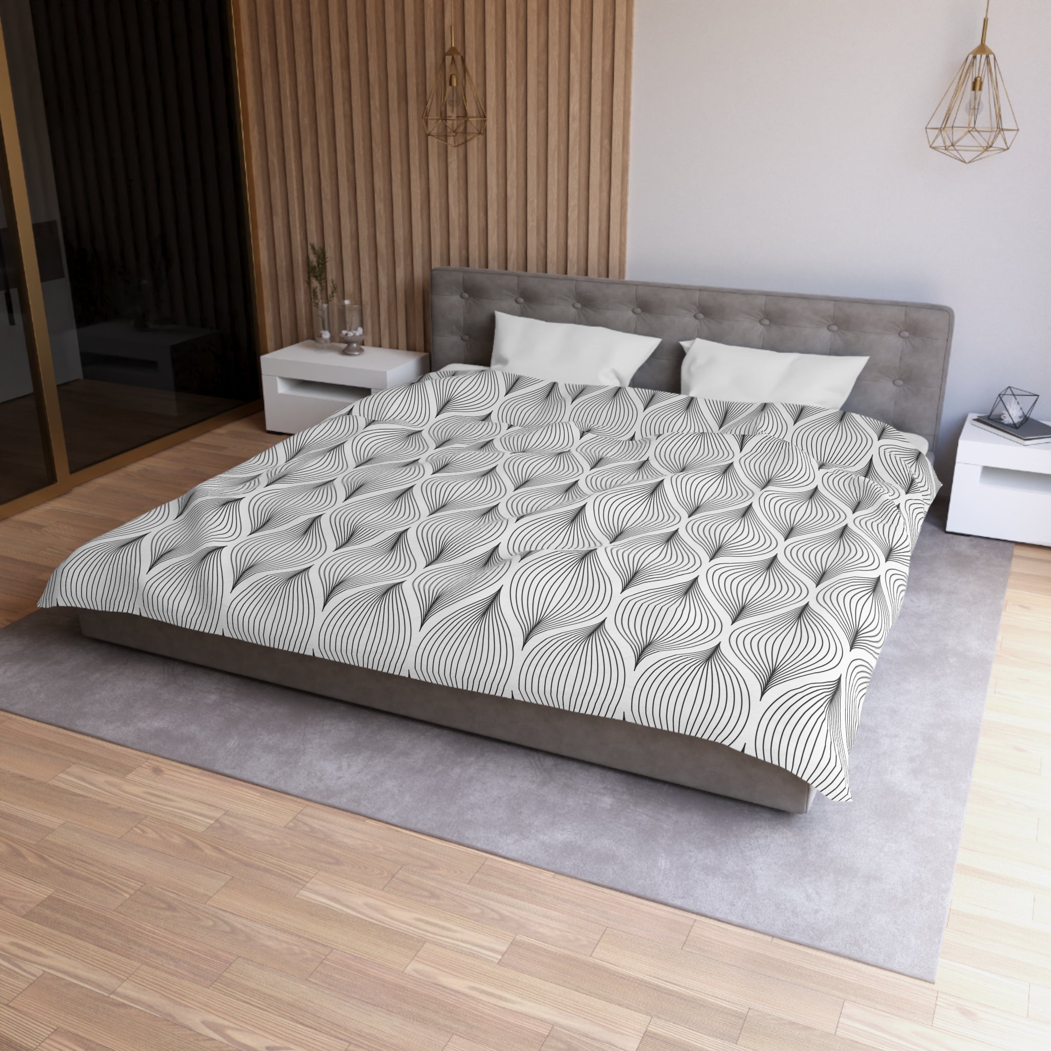 a modern bedroom with a large bed, a gray headboard, and a gray and white patterned comforter. The room has a wooden floor and a white nightstand on the left side. There is a pendant light hanging above the bed, and a vase on the nightstand. The overall design and color scheme of the room create a serene and stylish atmosphere.